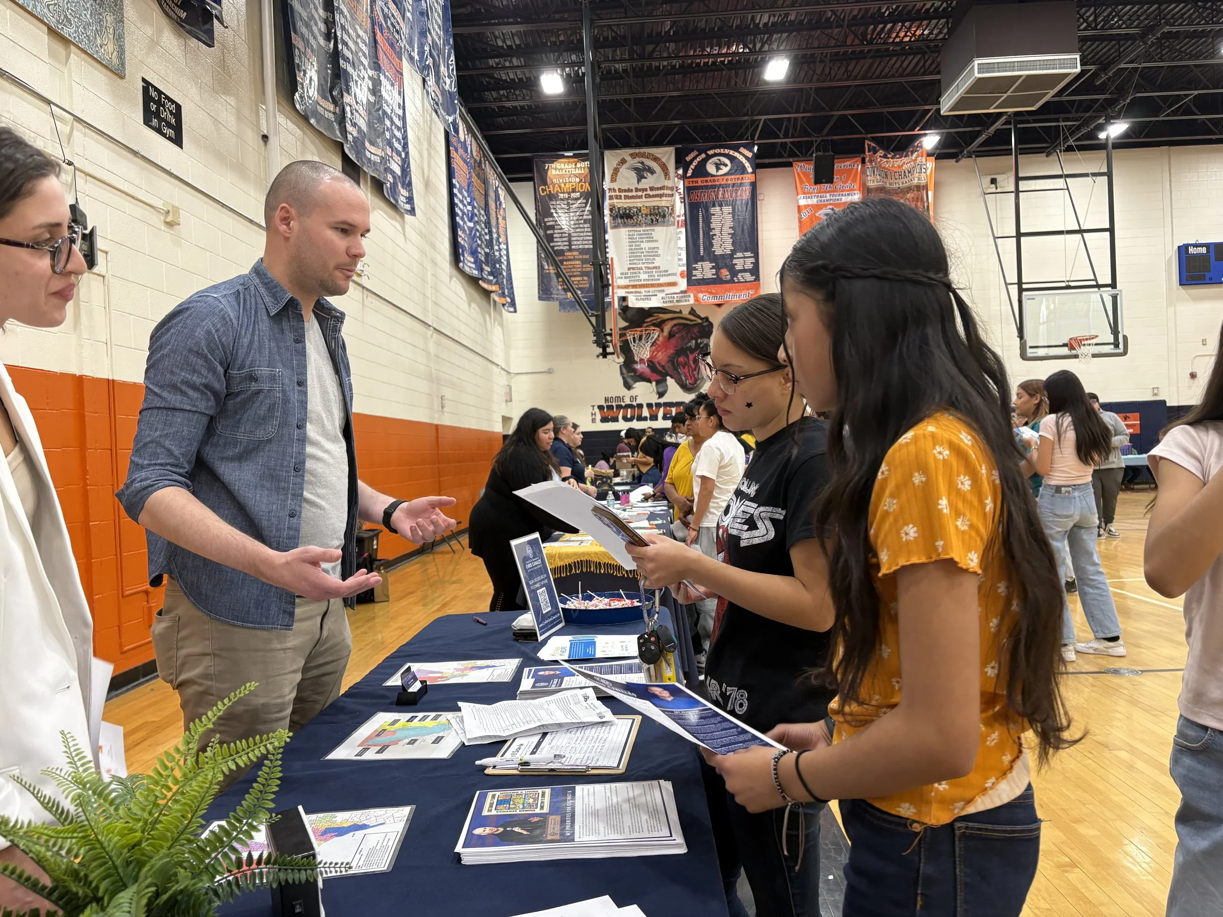 Chris engaging students at a resource fair booth in the Wiggs Middle School gymnasium.