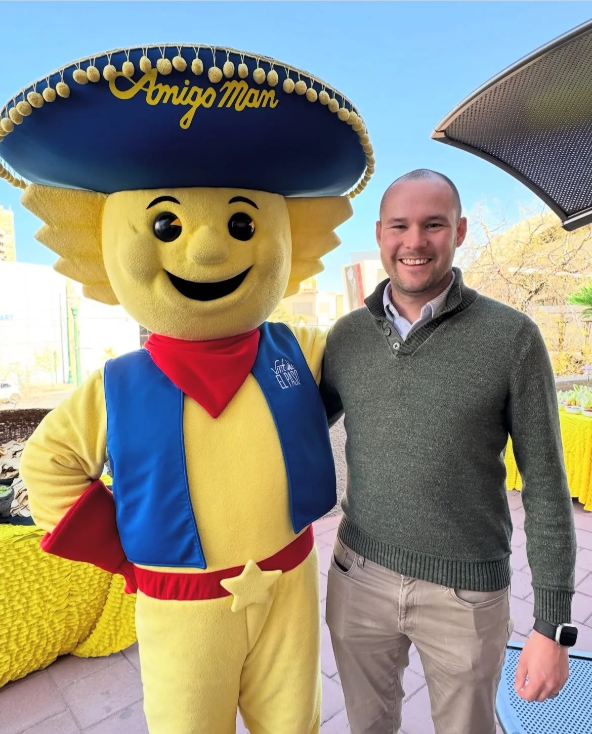 Chris and Amigo Man (El Paso's mascot) posing for a photo outdoors on a sunny day.