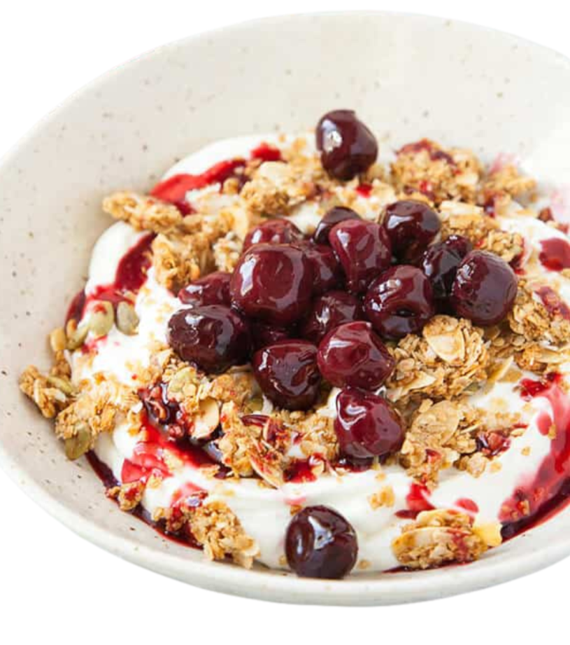 A bowl of yogurt topped with granola, blueberries, and a drizzle of berry sauce.