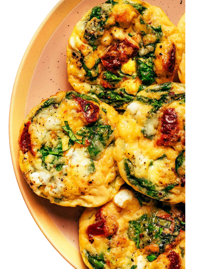 Baked egg muffins with spinach, cheese, and bacon on a beige plate.