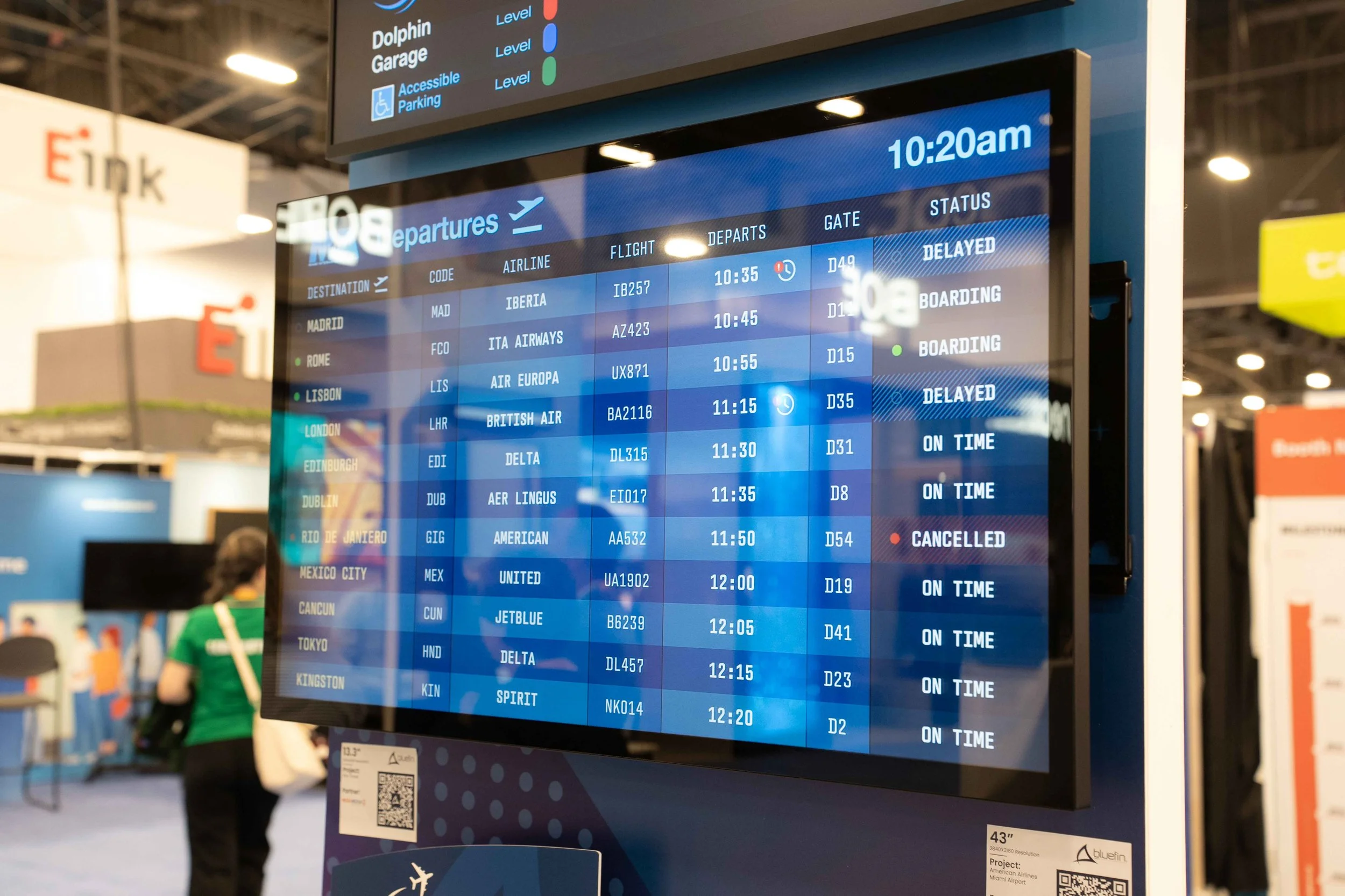 Commercial digital display showing an airport departures flight status board with flight numbers, destinations, gate assignments, and delay statuses.