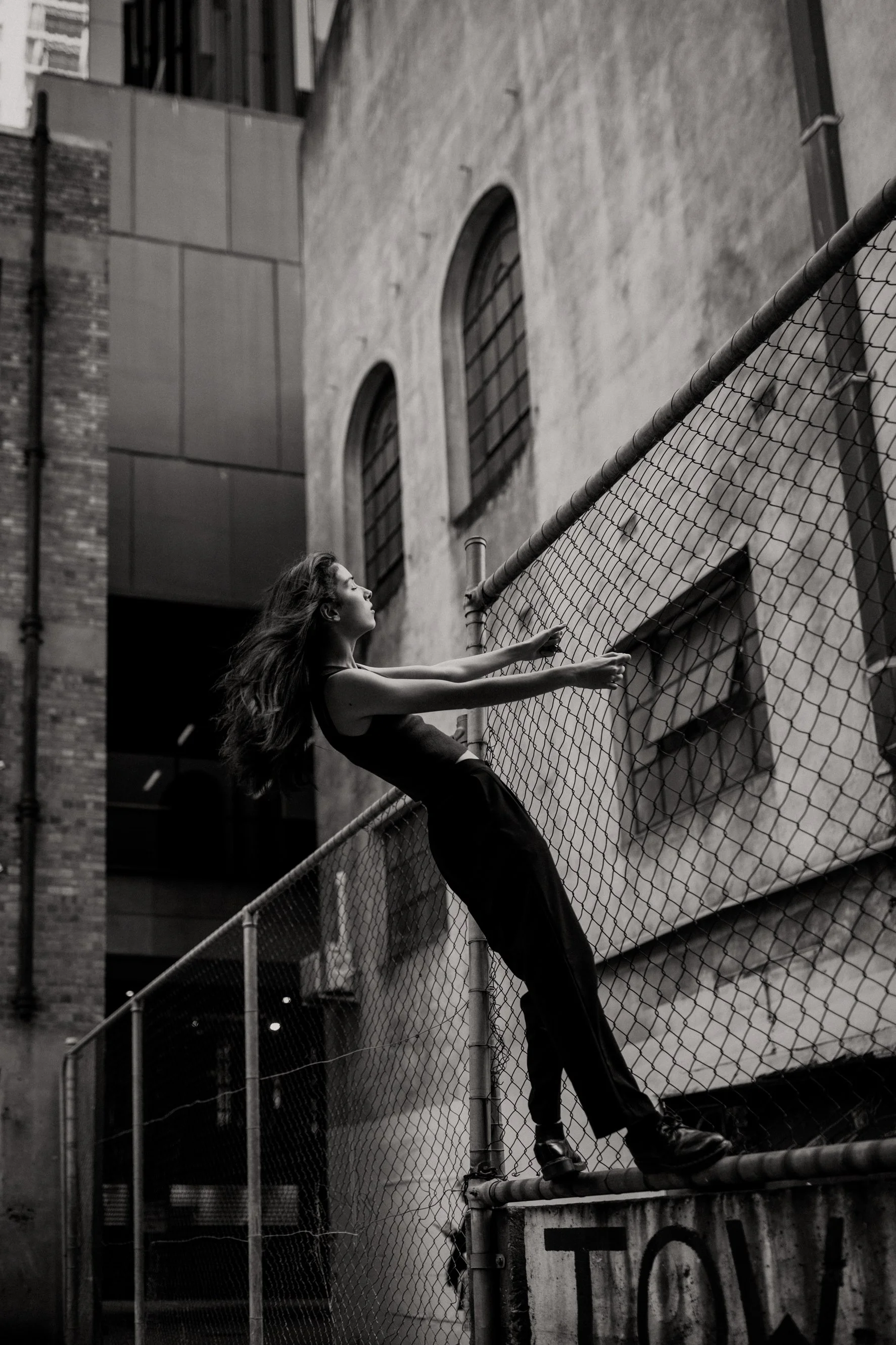 Musician holds onto wire fencing for artist branding photo shoot.