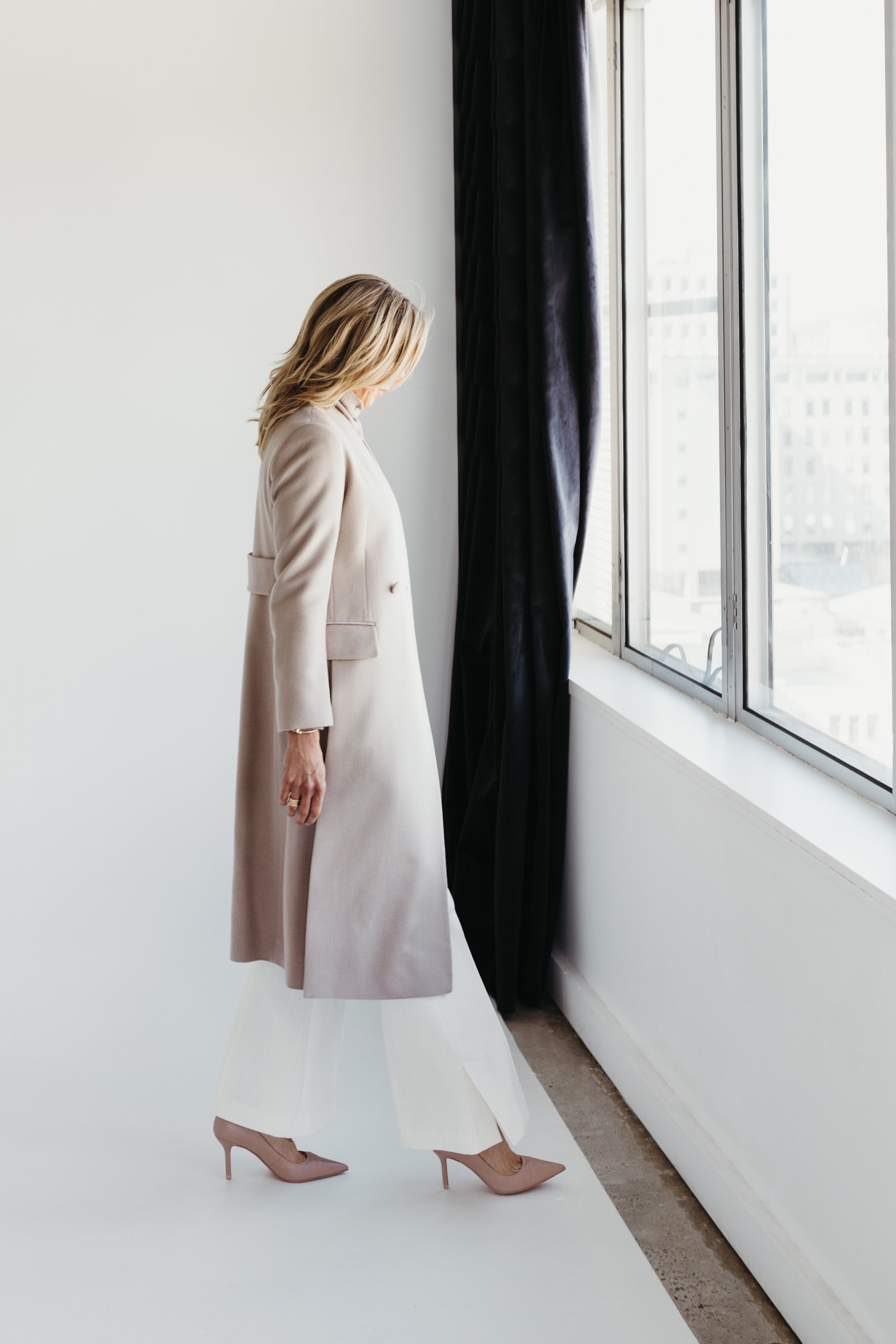 Woman walks in long woollen coat in studio for personal branding photo shoot in Hobart.