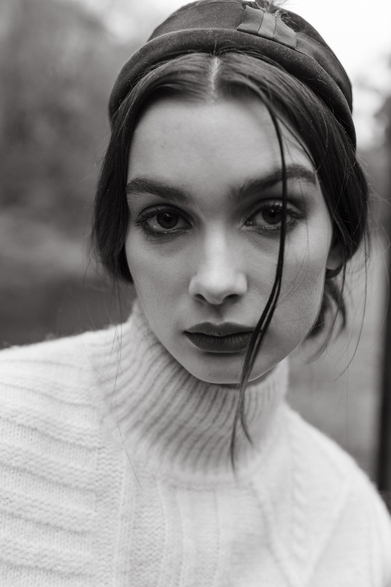 Model wearing vintage beret stares into camera with white knit.