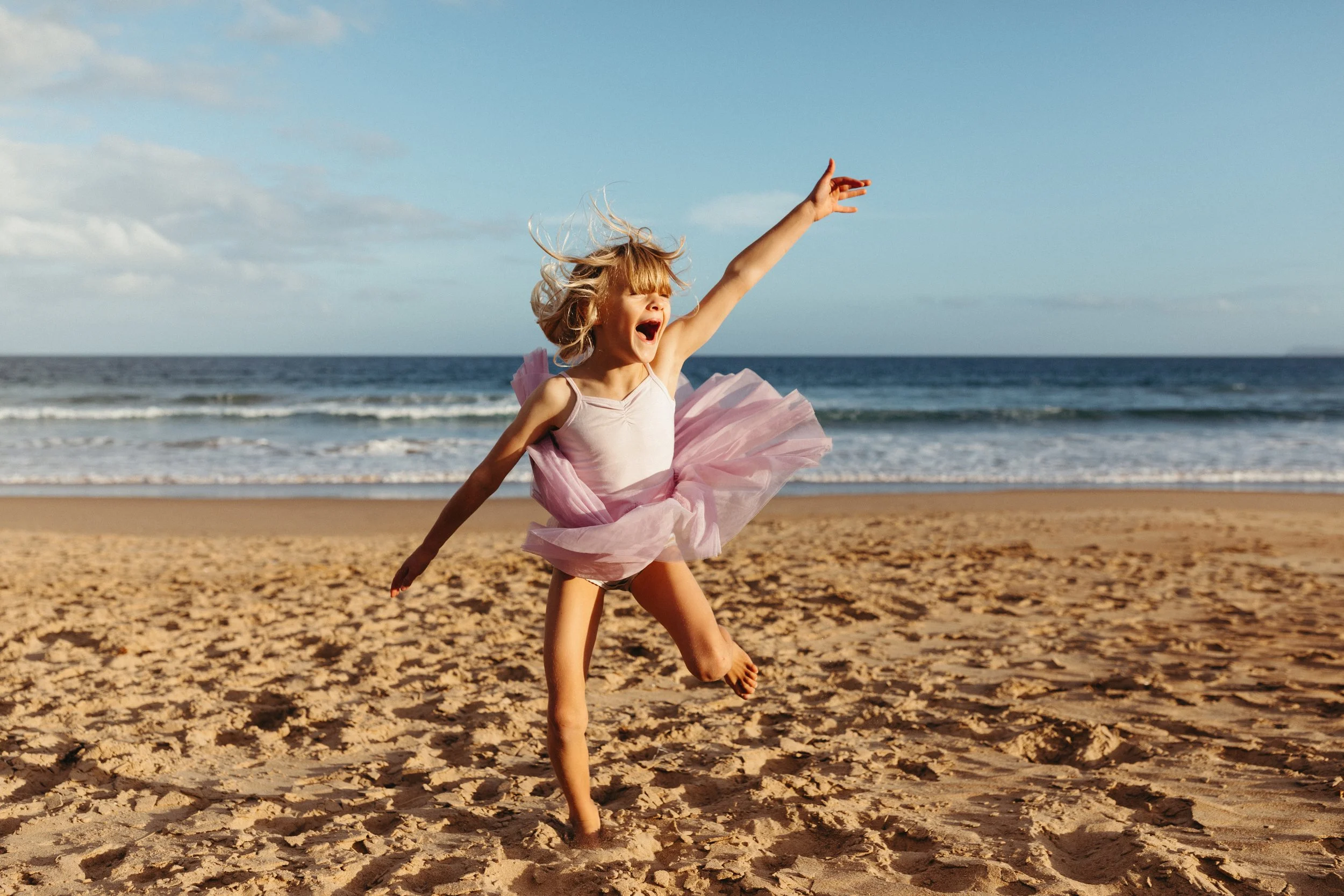 Young girl dances on beach during Peggy photo shoot in Tasmania.