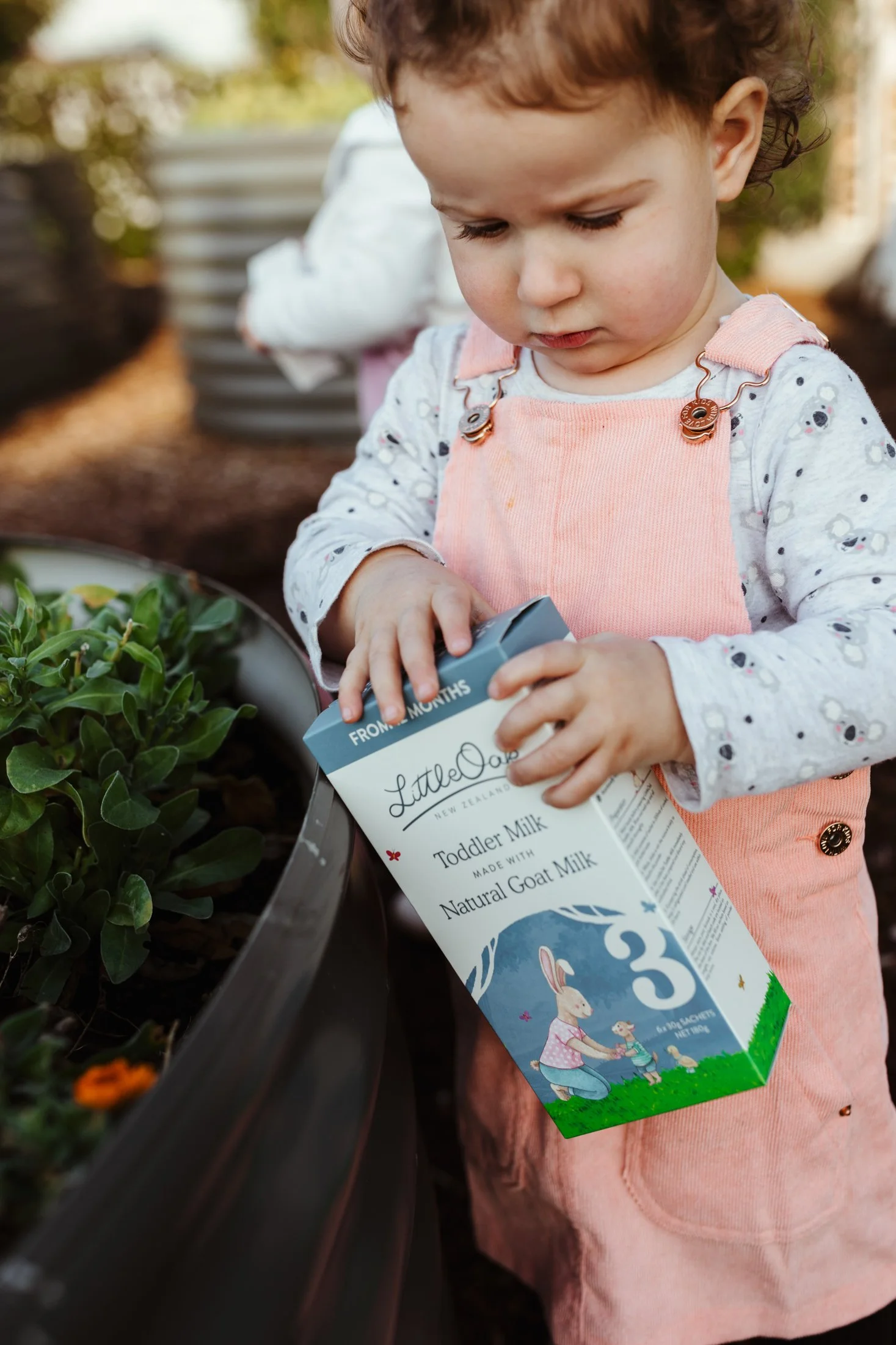 Child holds baby product in garden during event in Hobart.