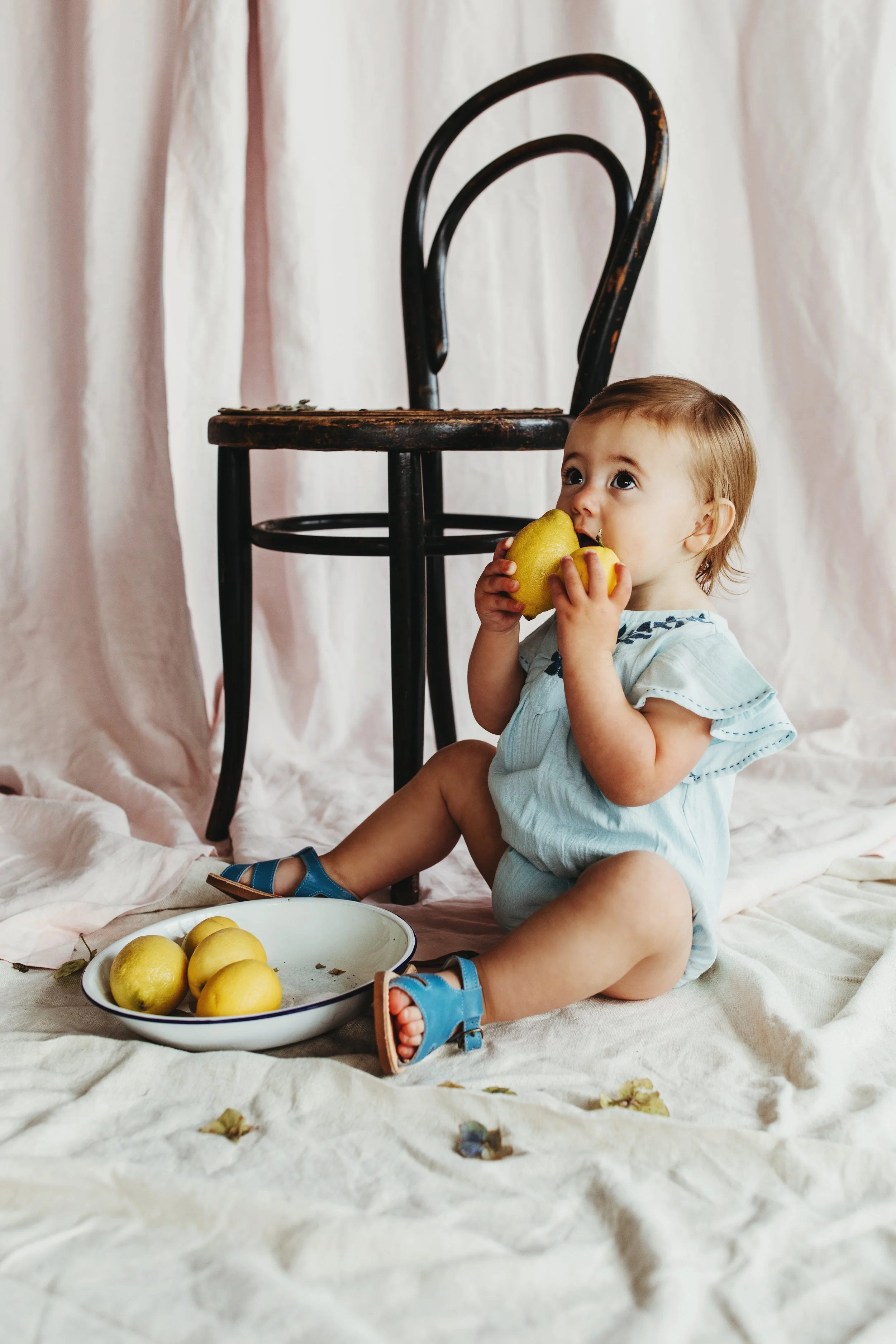 Baby sits in blue romper for kids clothing photo shoot in Hobart.