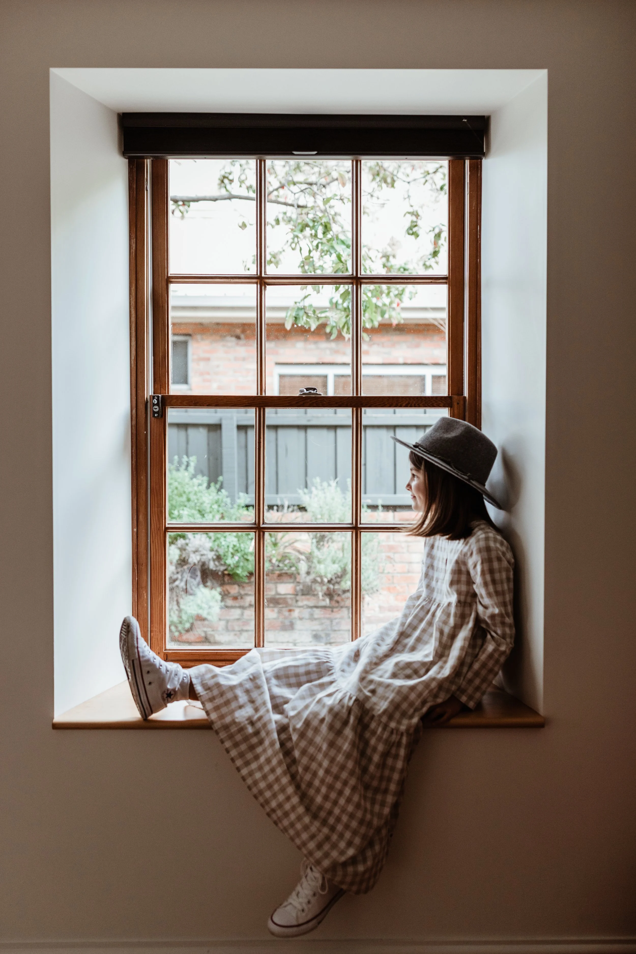Child sits in window seat of a beautiful Airbnb in Hobart, Tasmania.