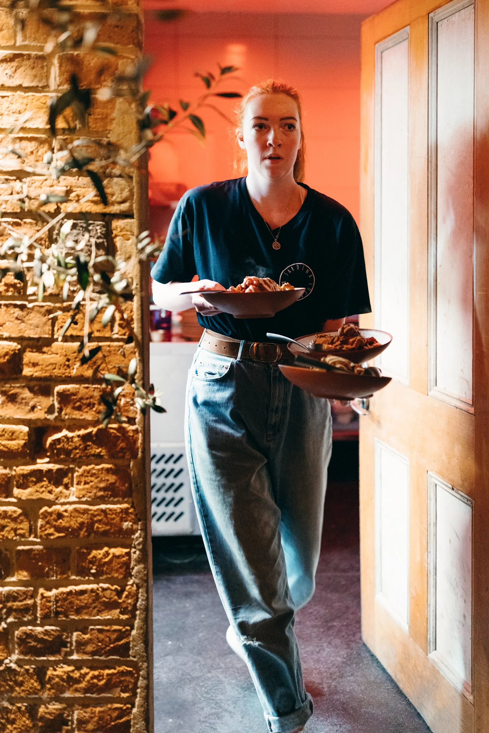 Waitress walks with plates in hand in restaurant.