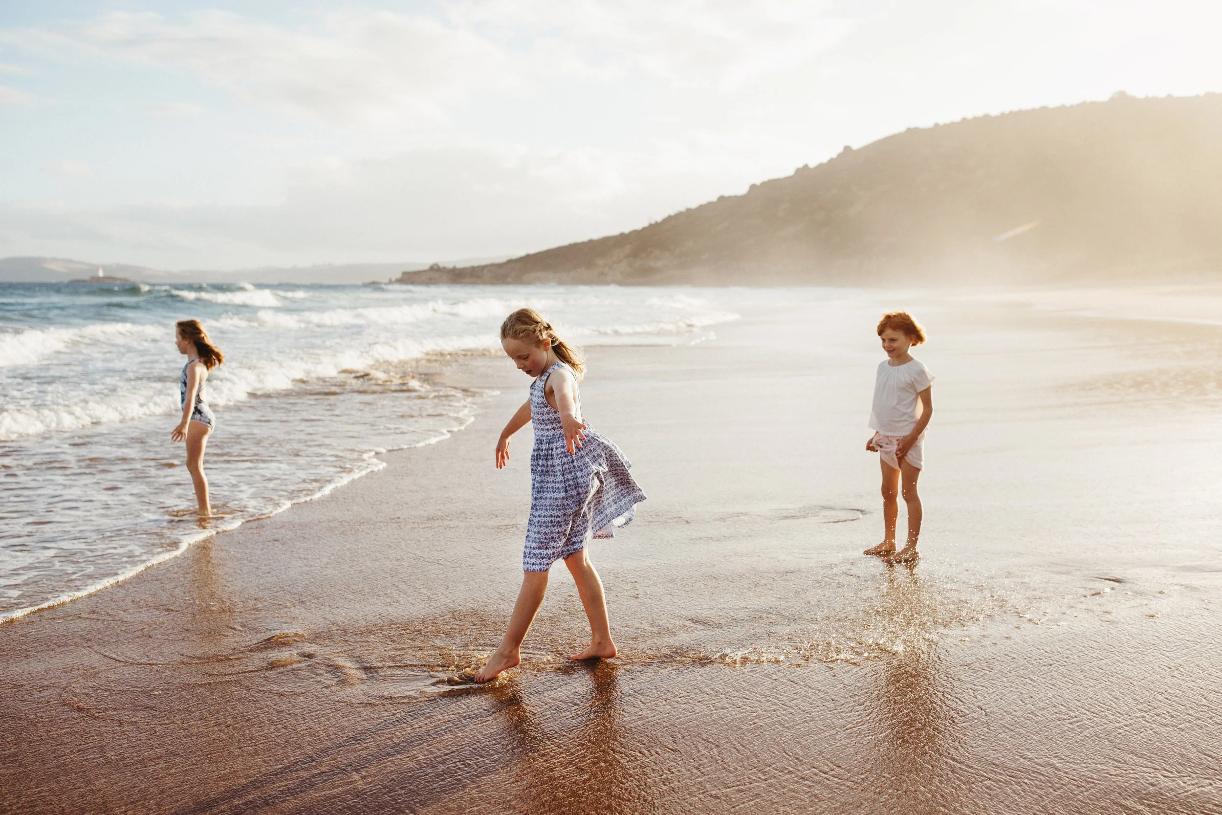 Girls play at shoreline during sunset campaign shoot.