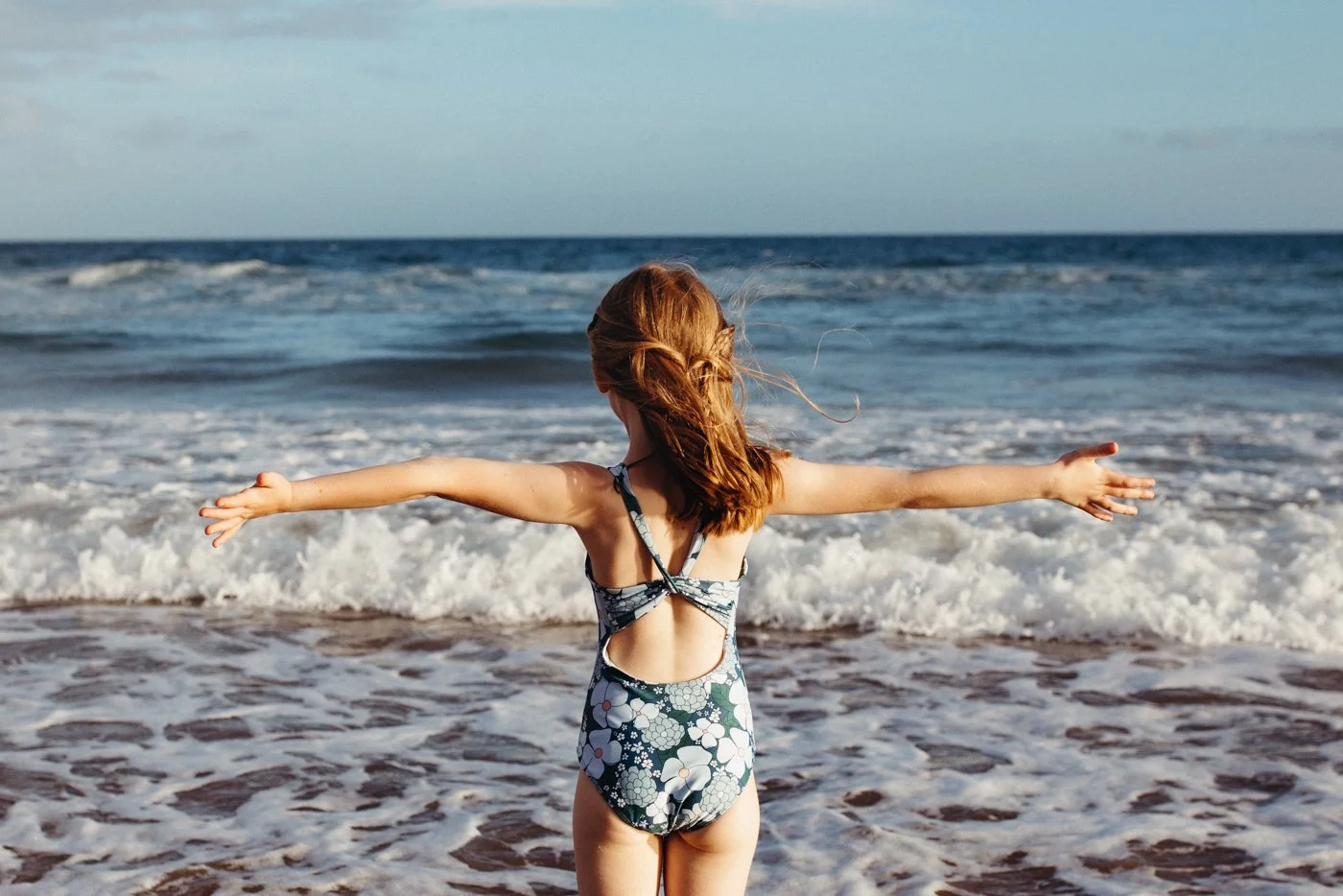 Young girl embraces the ocean during Peggy clothing campaign shoot.