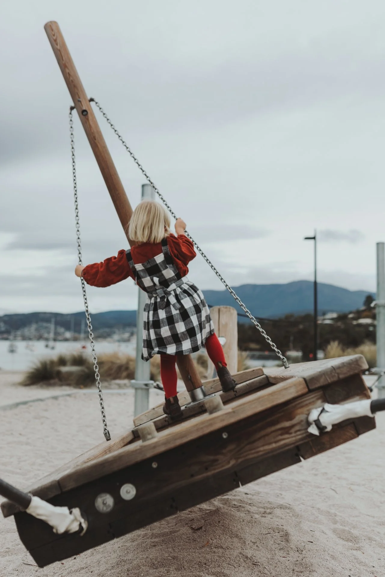 Girl plays on wooden boat in cute clothing in Hobart.