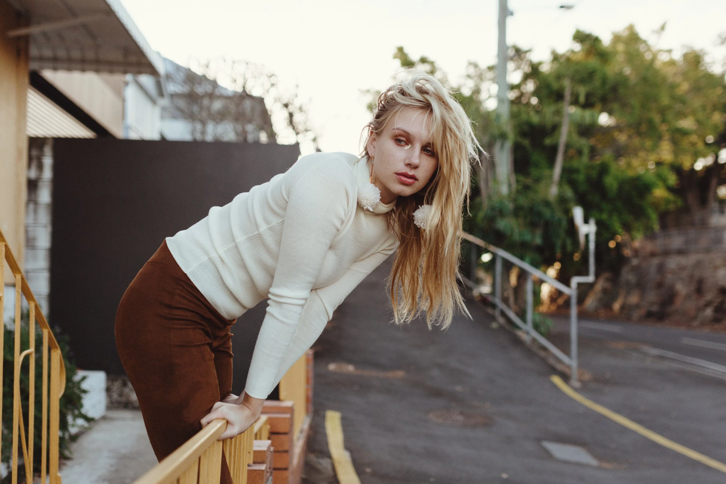 Model leans over railing in Brisbane street for photo shoot.