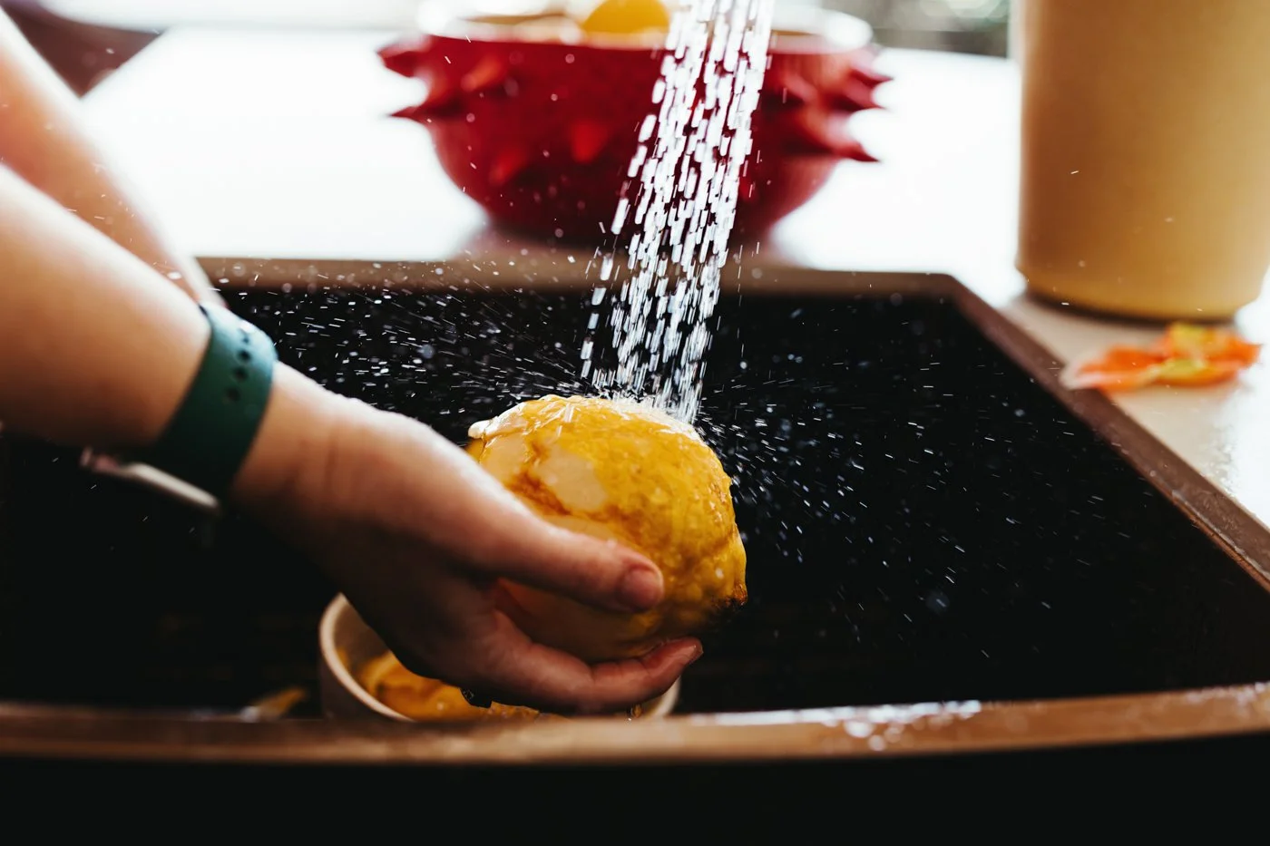 Close up of chef's hands washing quince in sink for recipe book photography.