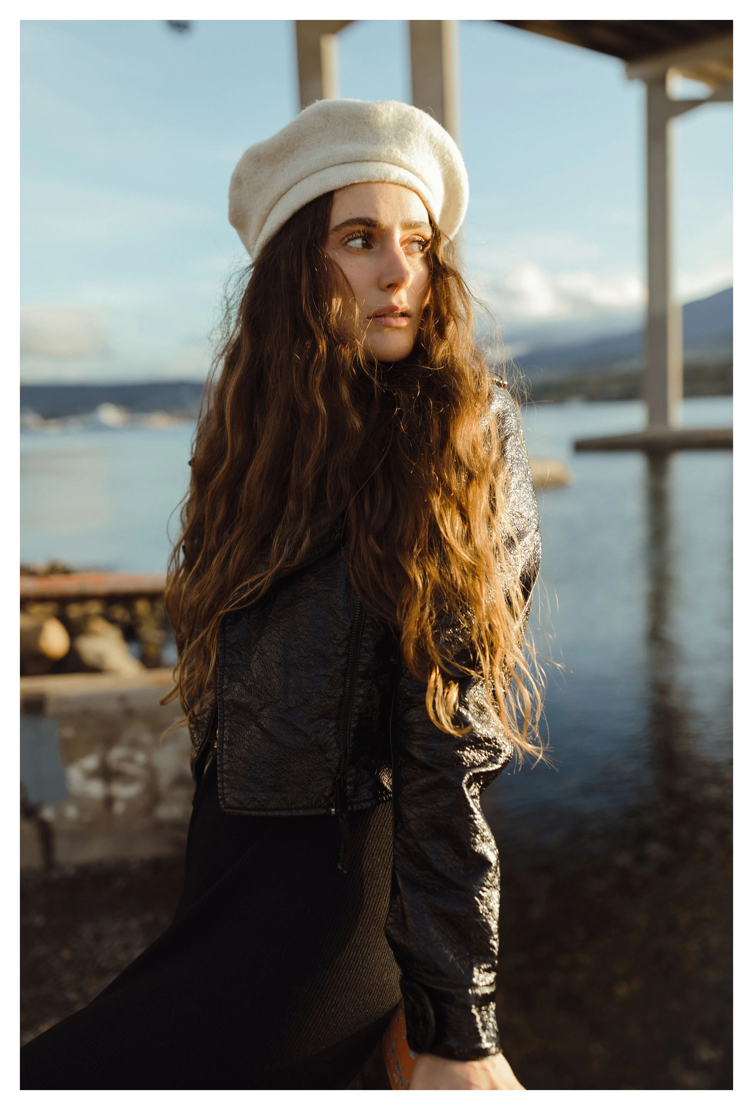 Fashion model poses in white beret by a river in Hobart.