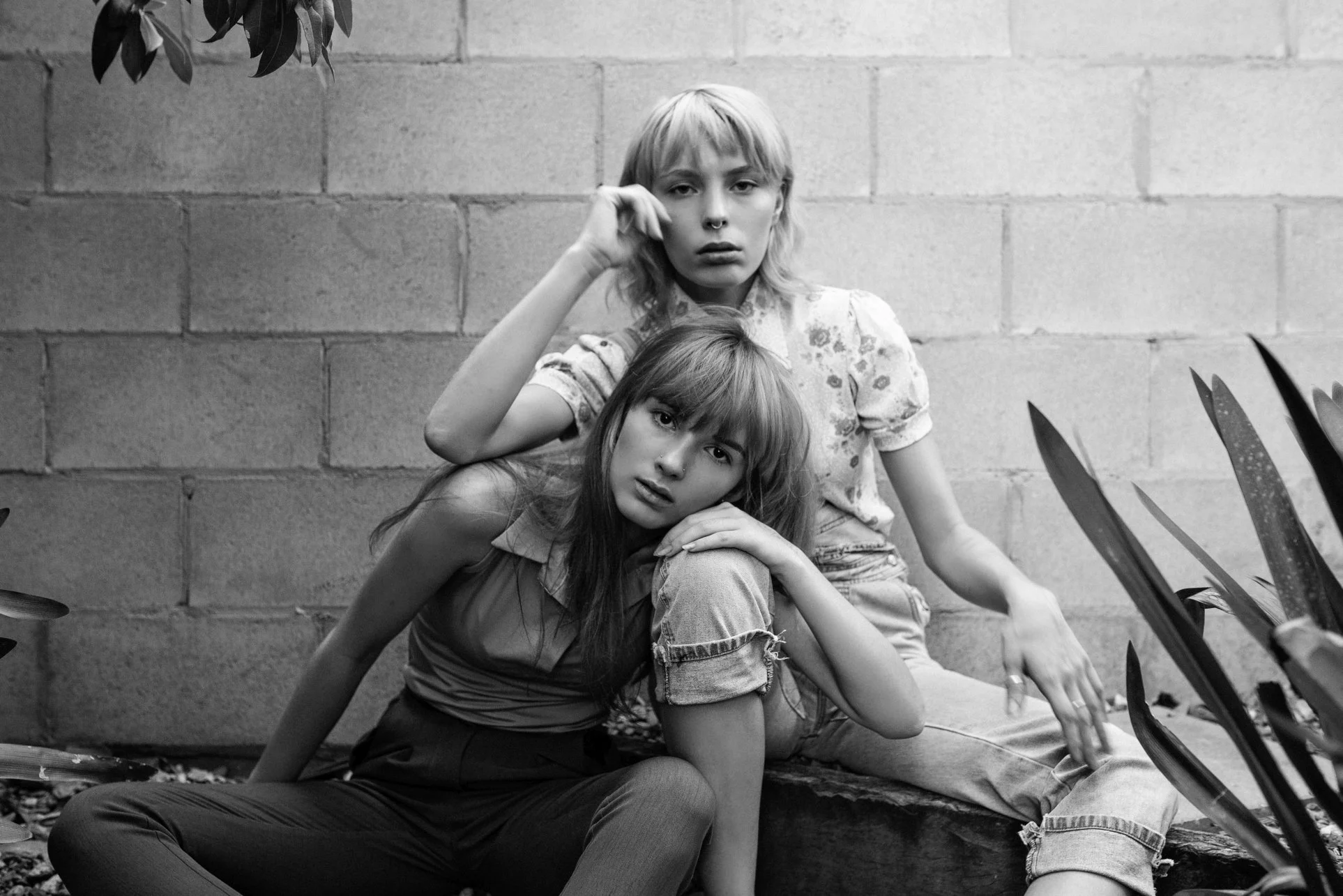 Two models pose together in garden.