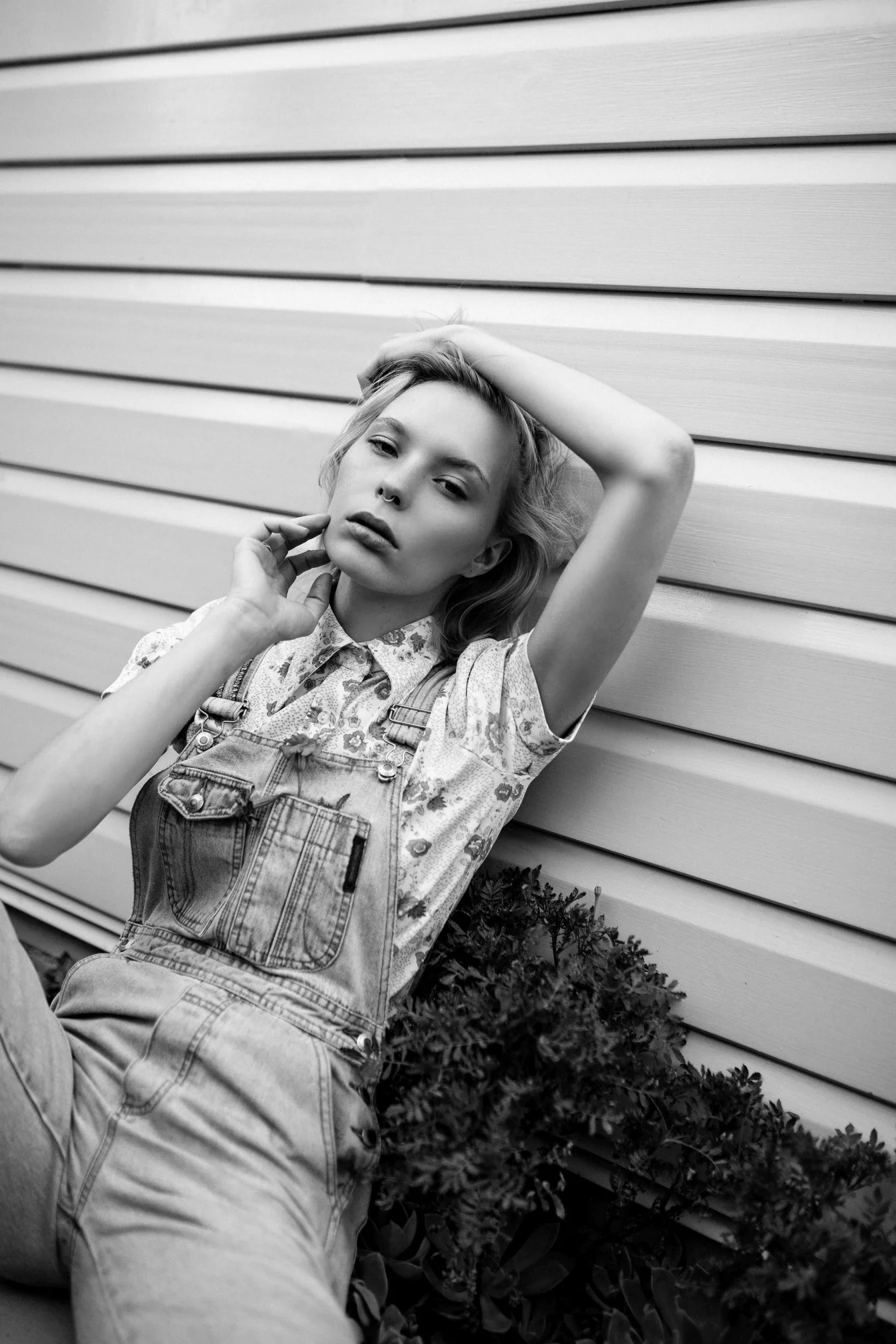 Model leans against house in denim overalls in Brisbane fashion shoot.