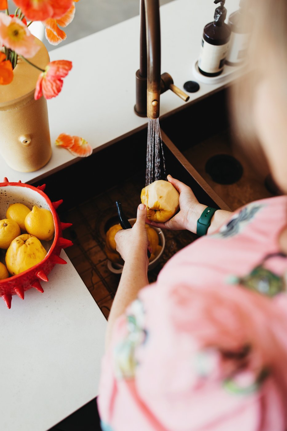 Food writer/author washes quince in sink.