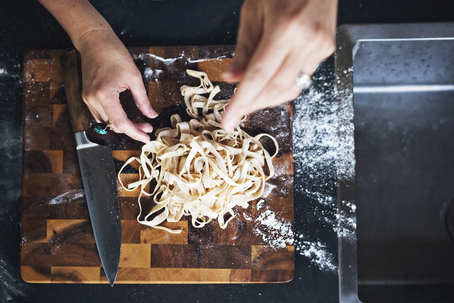 Overhead image of hands separating pasta strands.