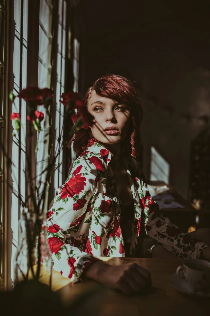 Model sits beside window, looking out in test shoot.