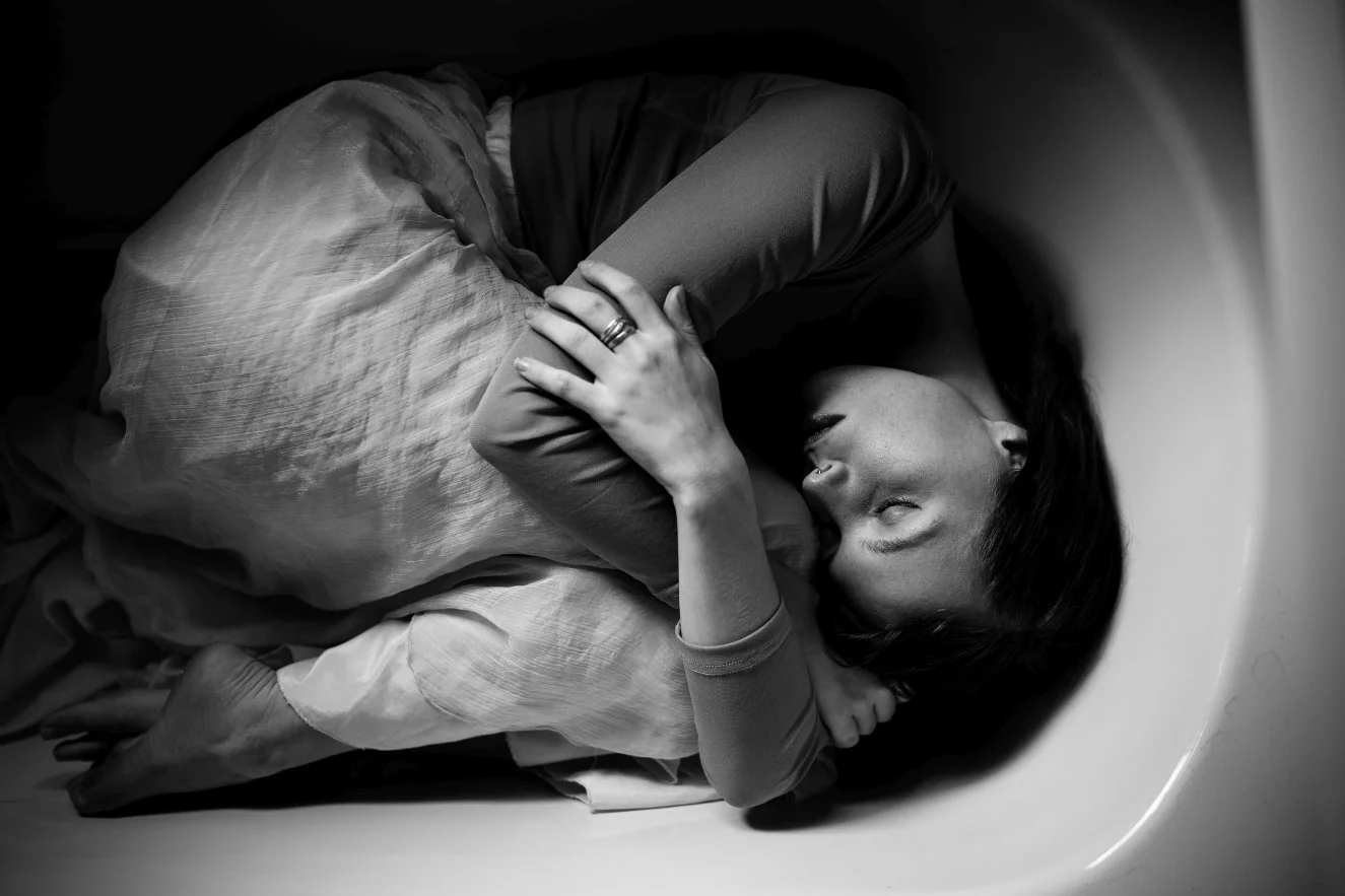 Model lies in bath for portrait shoot.