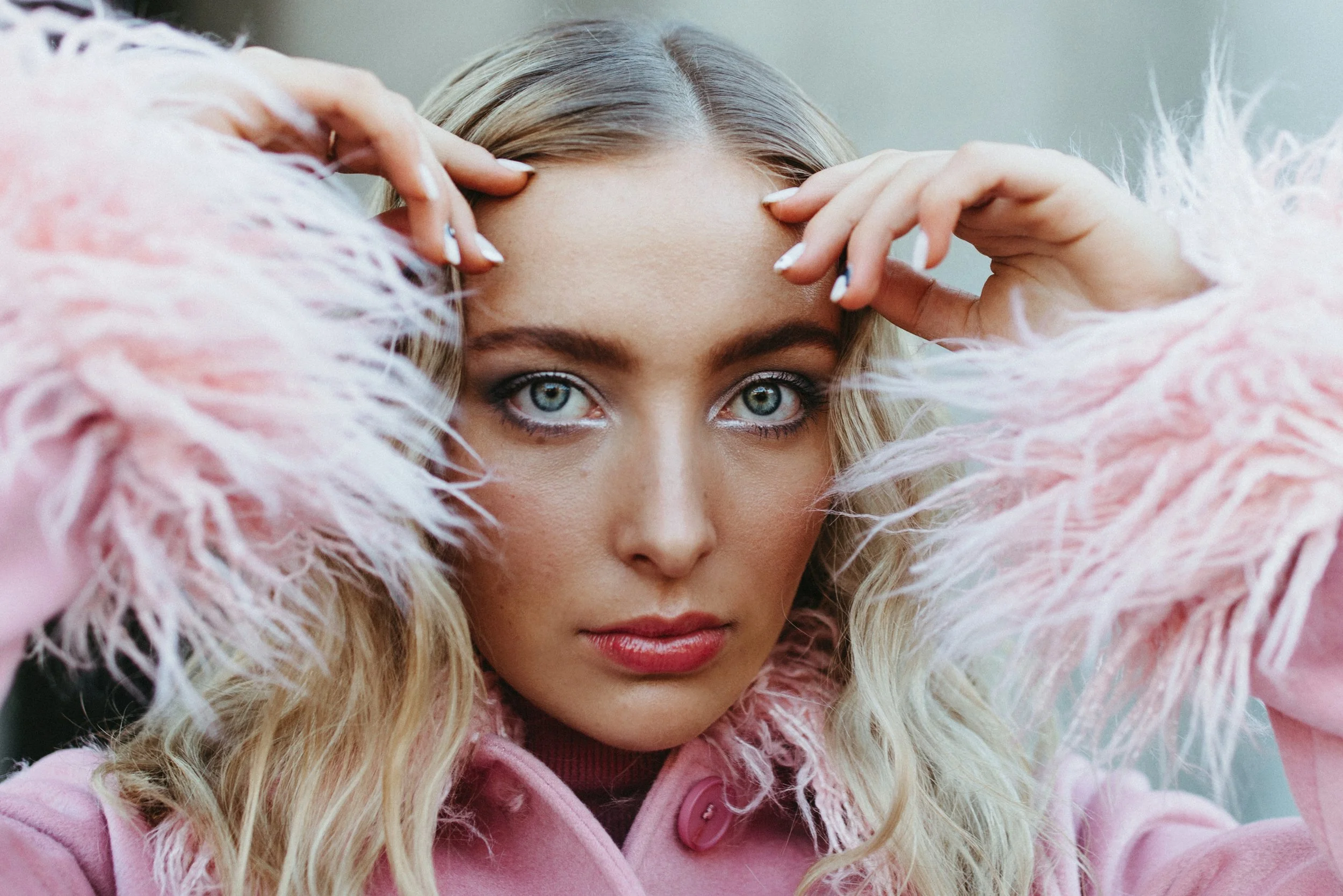 Model wearing fluffy pink jacket looks into camera for test shoot.
