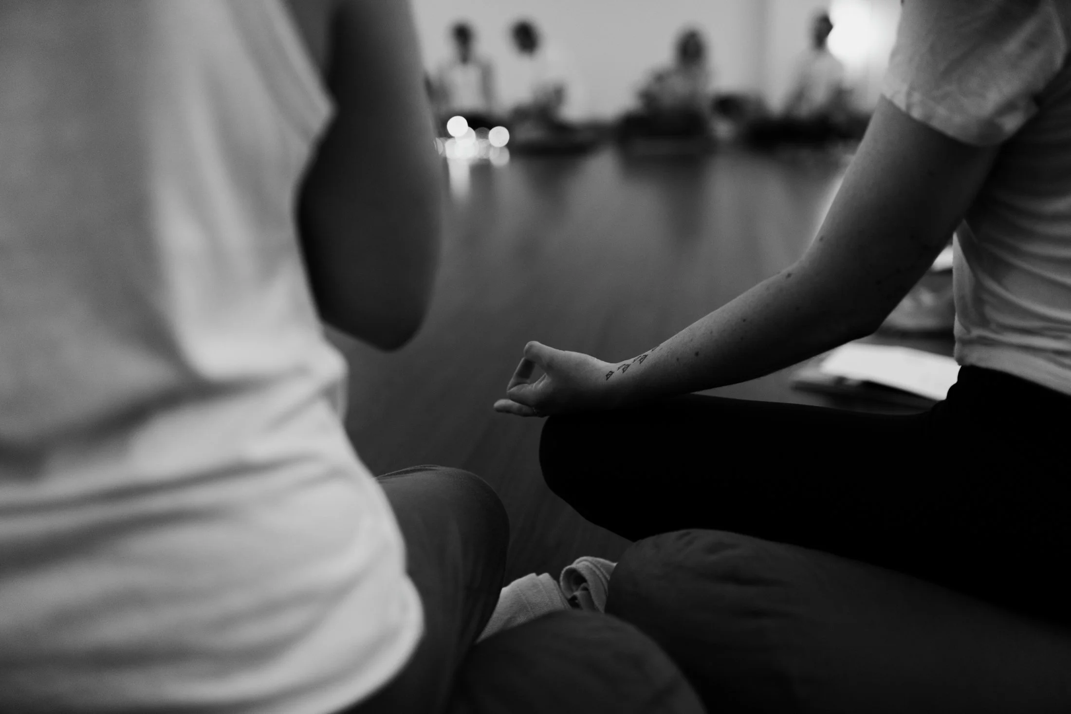 Black and white image of hands in prana mudra during yoga event.