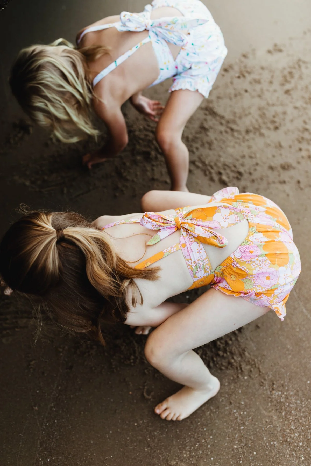 Girls digging sand at beach for photo shoot in Hobart.