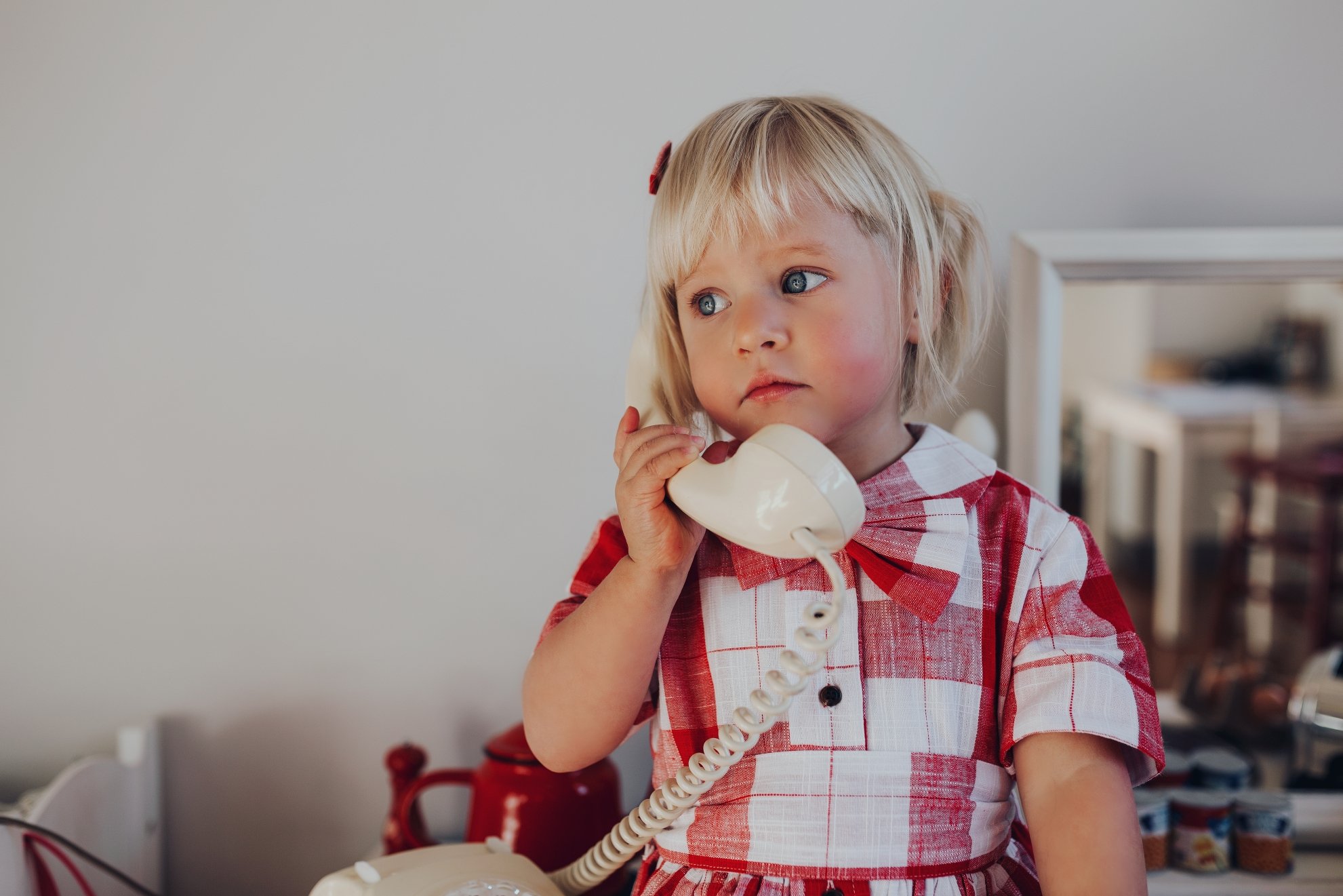 Young girl holds vintage phone in fashionable outfit.