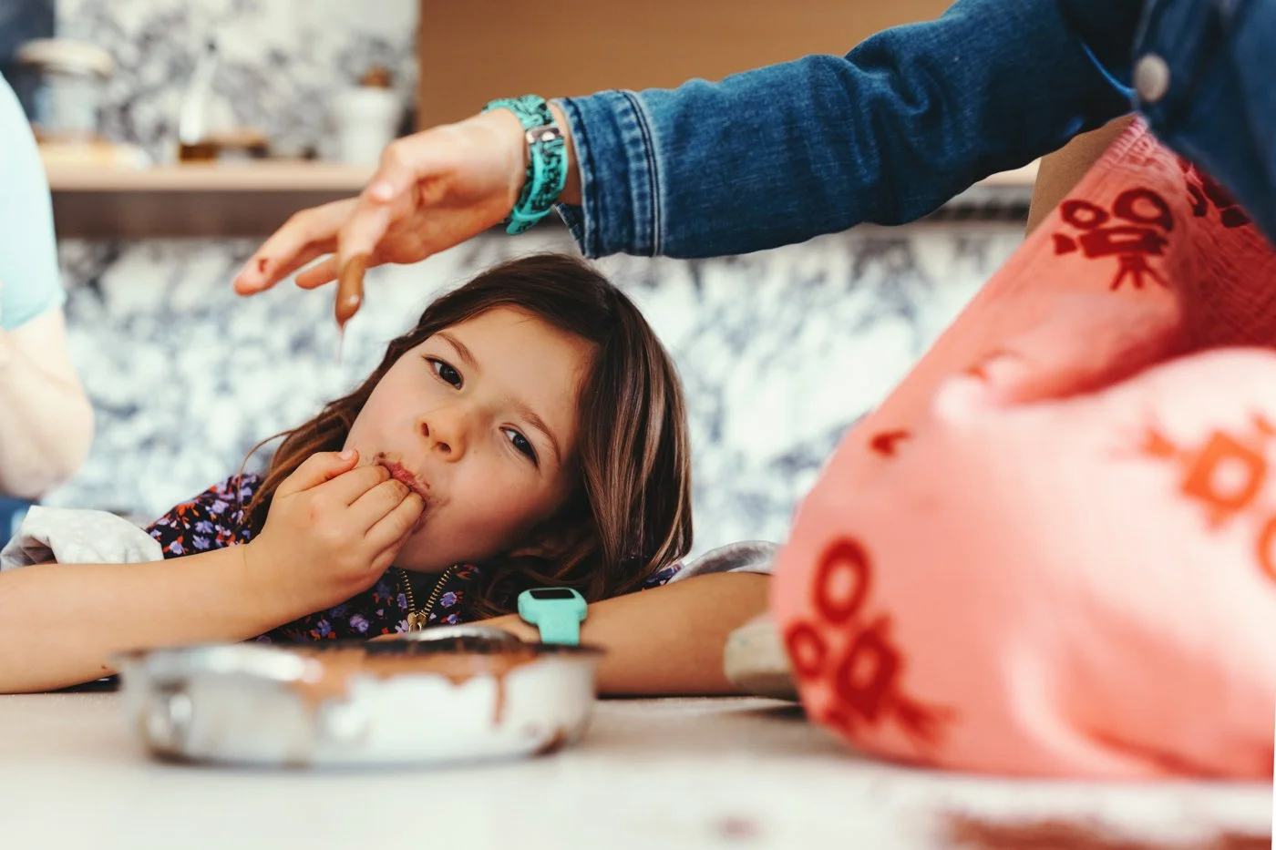 Child licks bowl of chocolate cake batter for recipe book photo shoot.