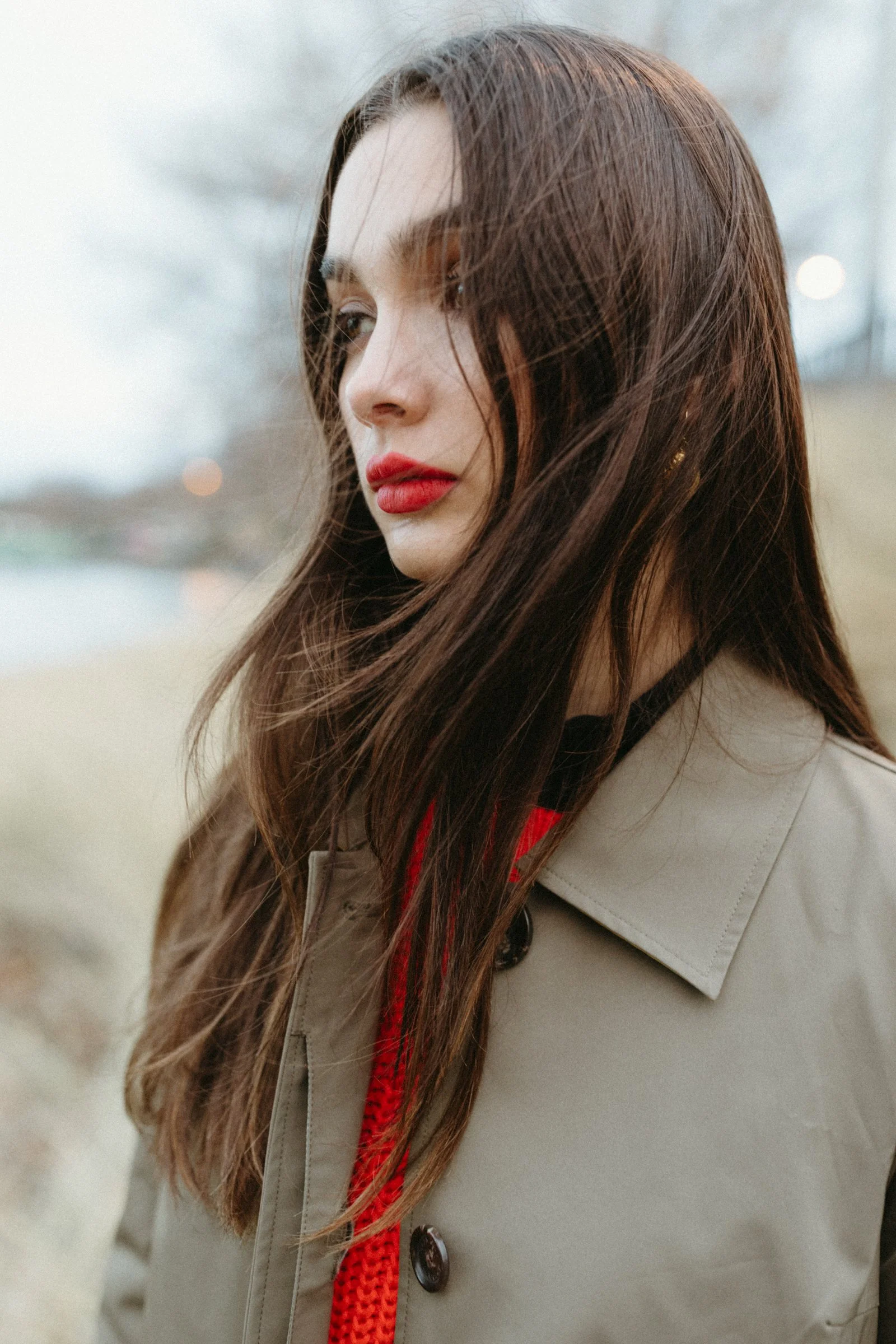Woman stands on beach at sunset with bright red lipstick.