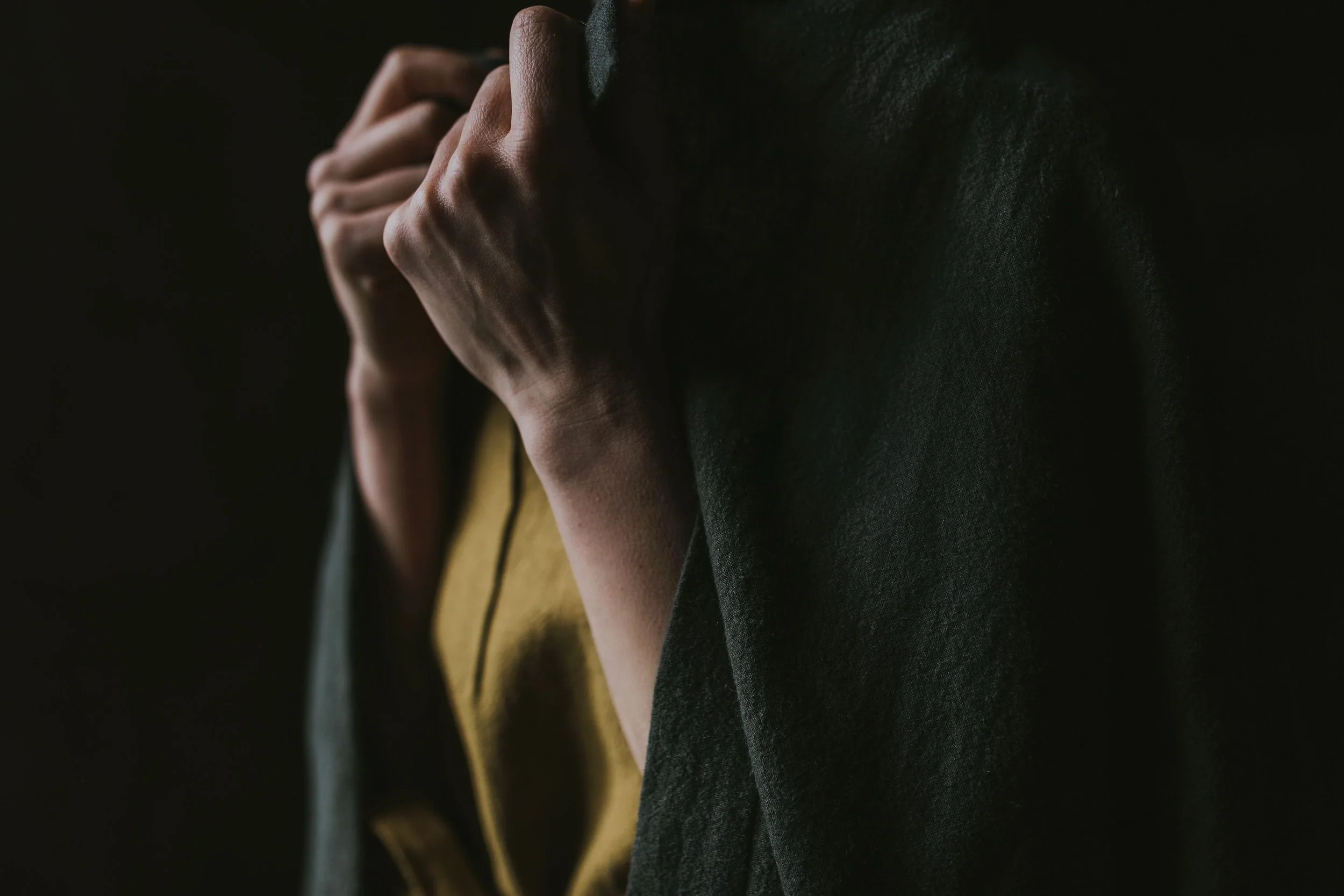 Close up of hands holding wool cardigan for commercial client.