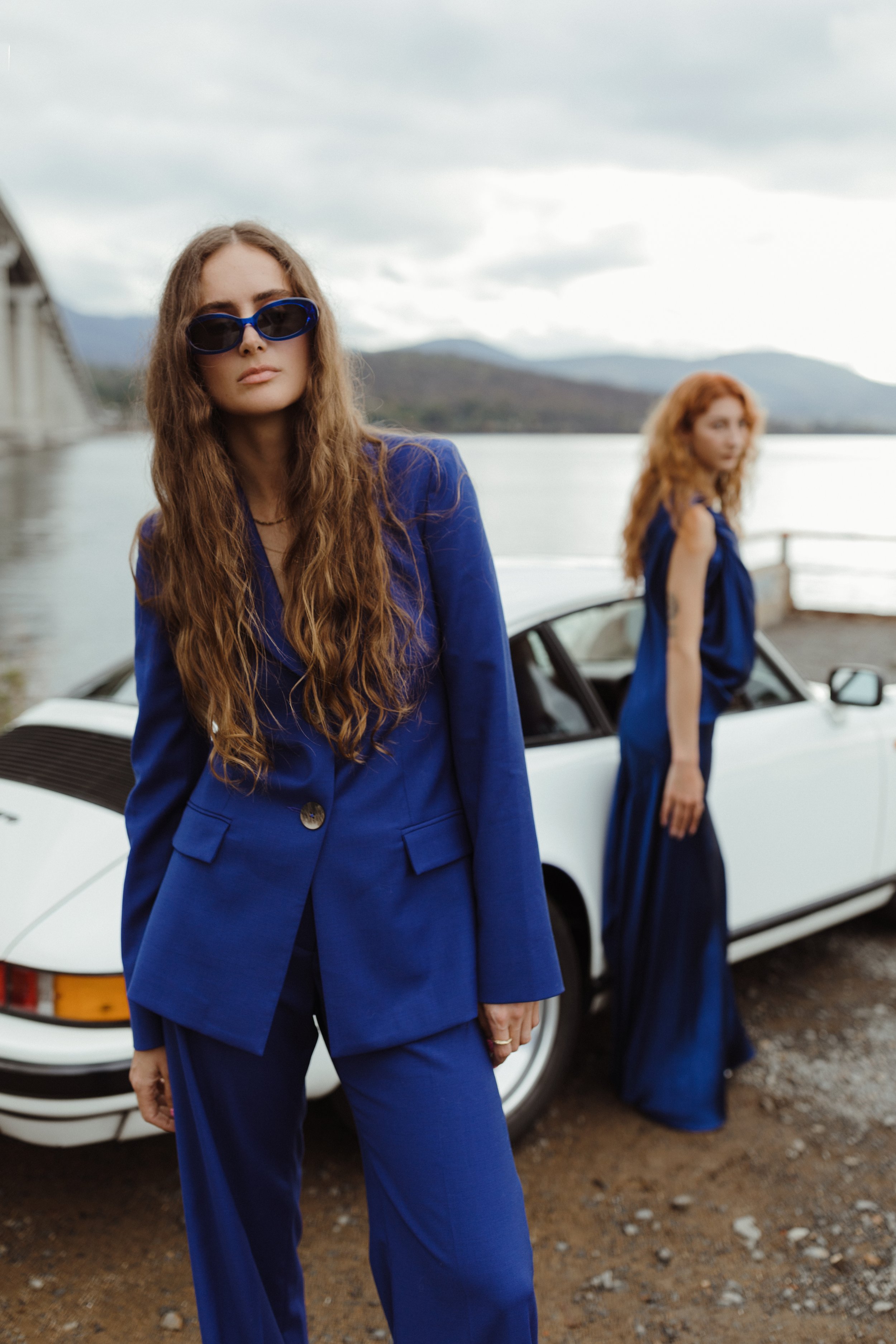 Models pose in front of vintage porsche for fashion photography.