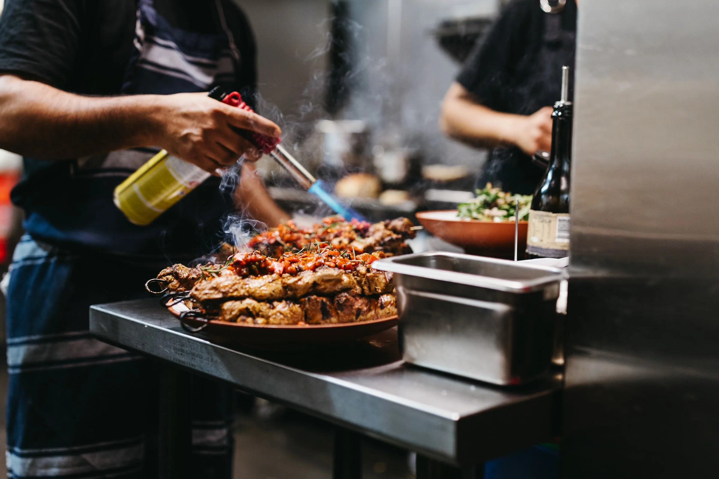 Chef fires a meat dish in busy restaurant.