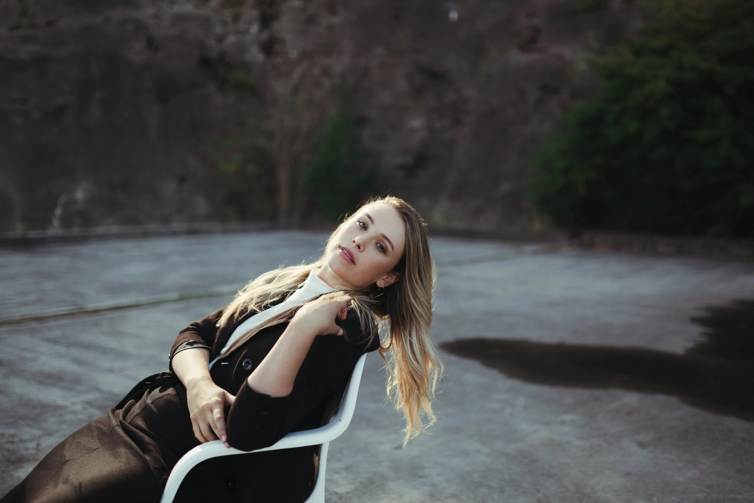 Model sits in chair with sun shining on her face in Hobart.
