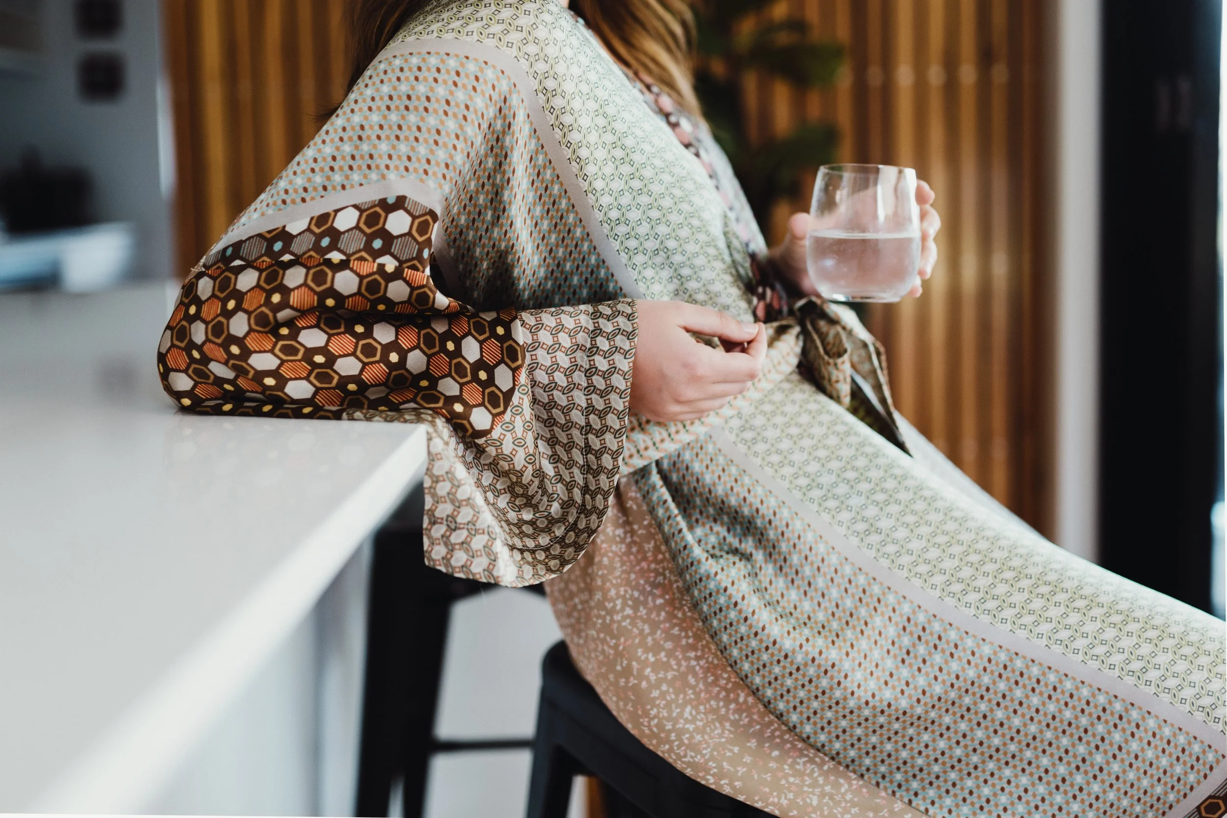 Woman sits at bench with glass of water for commercial photo shoot.