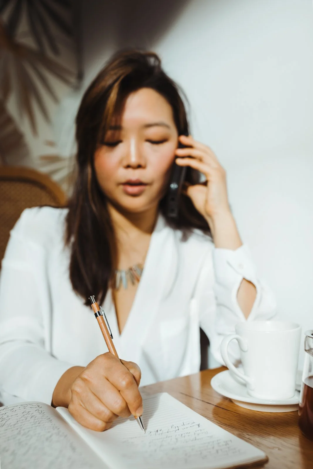 Woman takes notes as she speaks on phone for lifestyle branding session in Hobart.