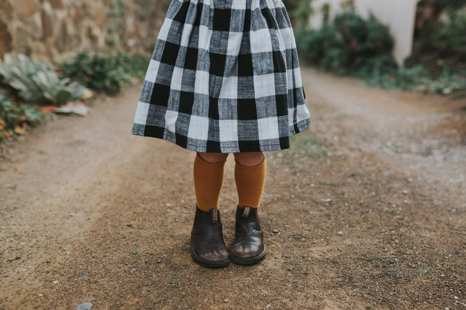 Girl wears gingham dress and Blundstone boots.
