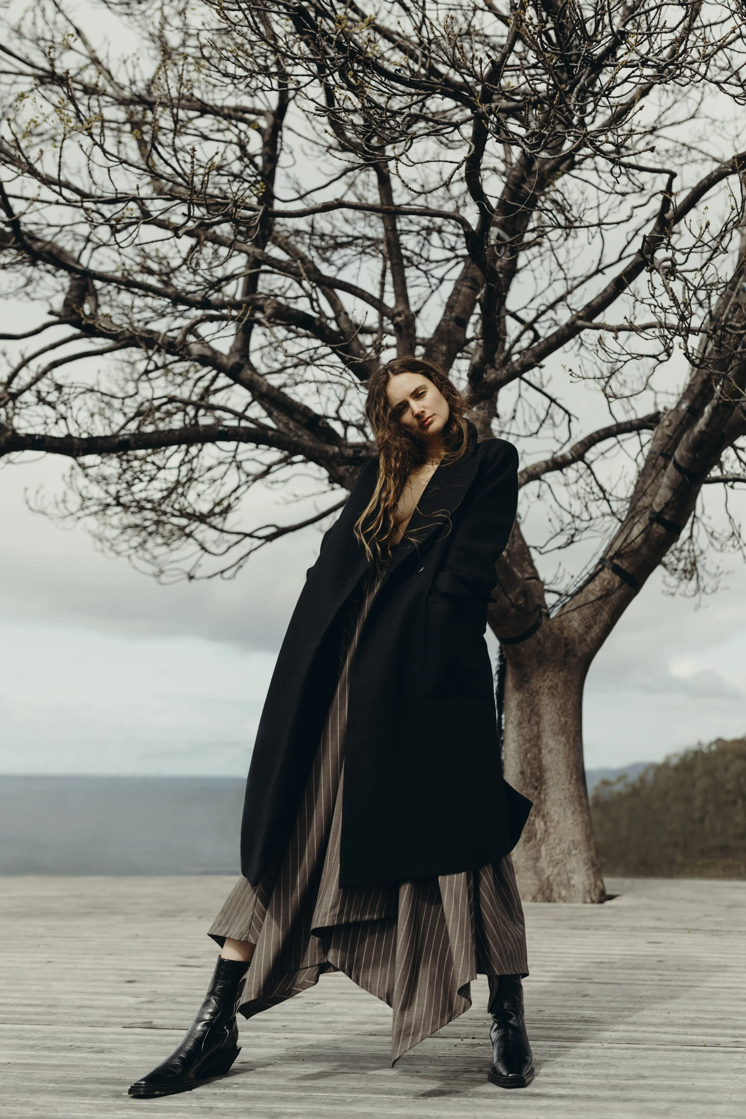 Model poses on deck with Tasmanian ocean behind her.