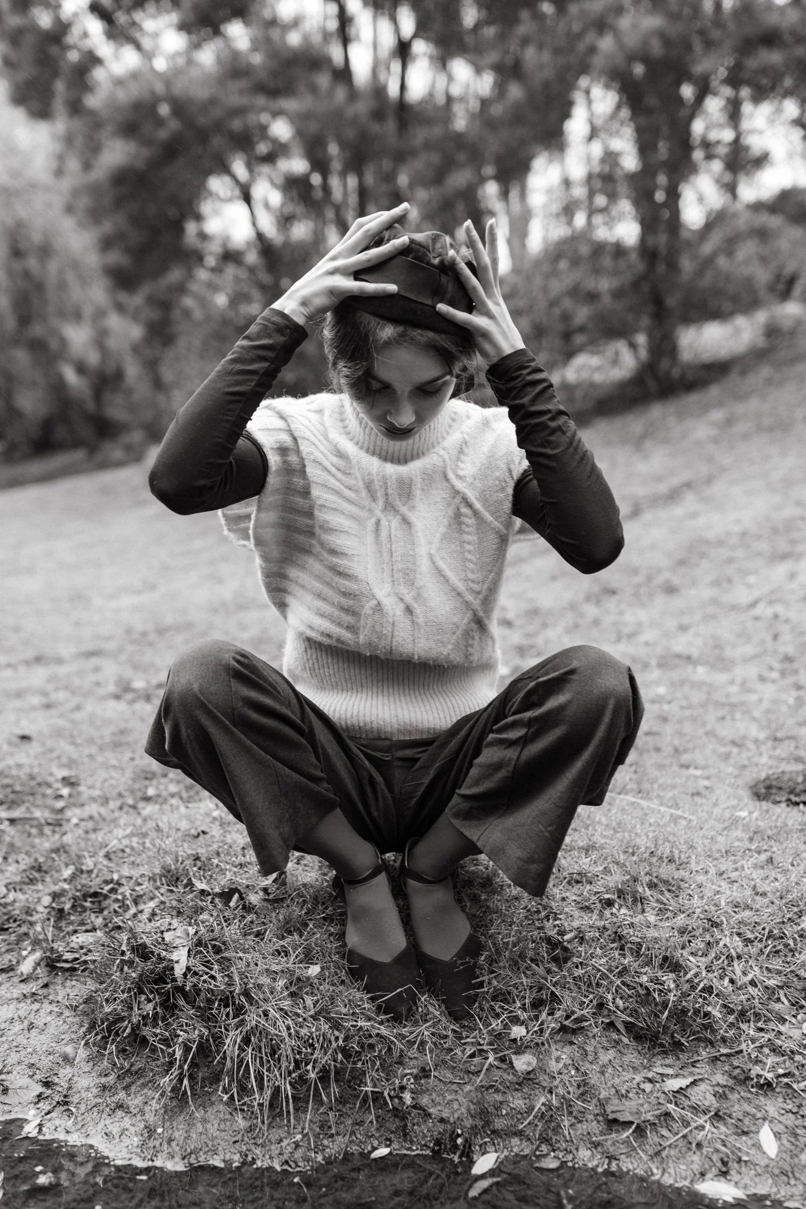 Model places hat on her head beside a Tasmanian river.