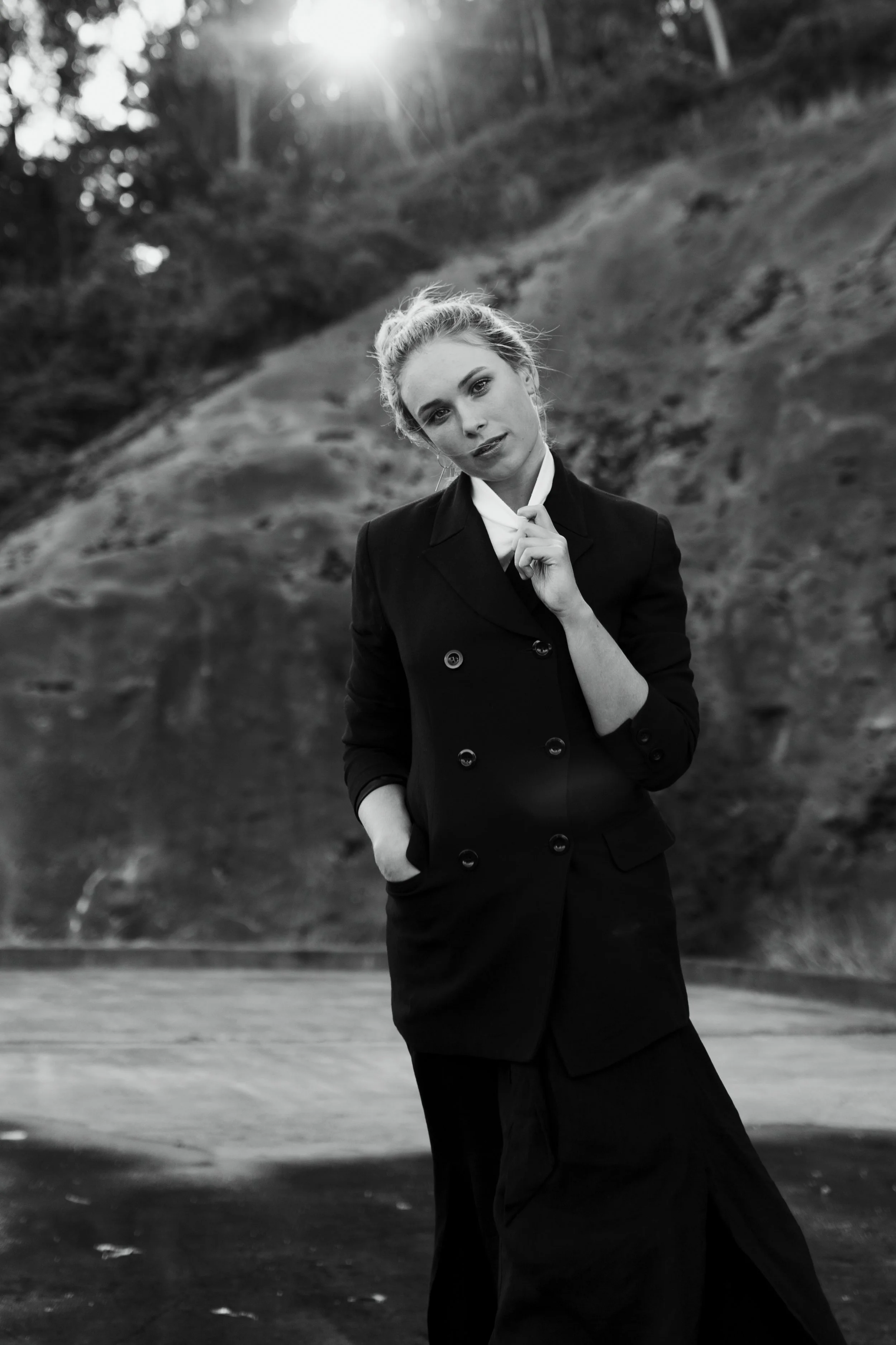 Woman walks with sunflare behind her during model photo shoot.