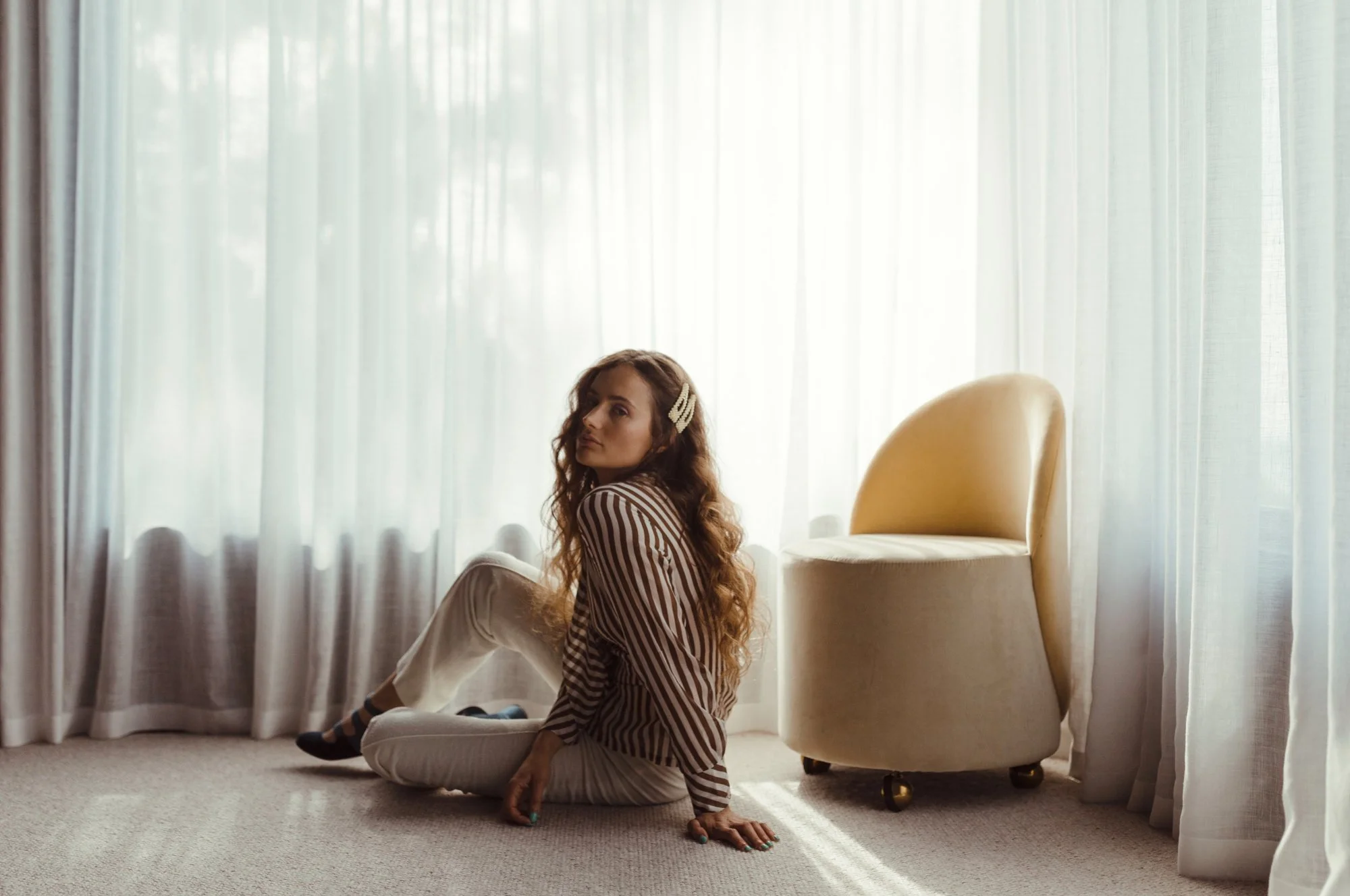 Woman sits on floor in vintage high end photo shoot.