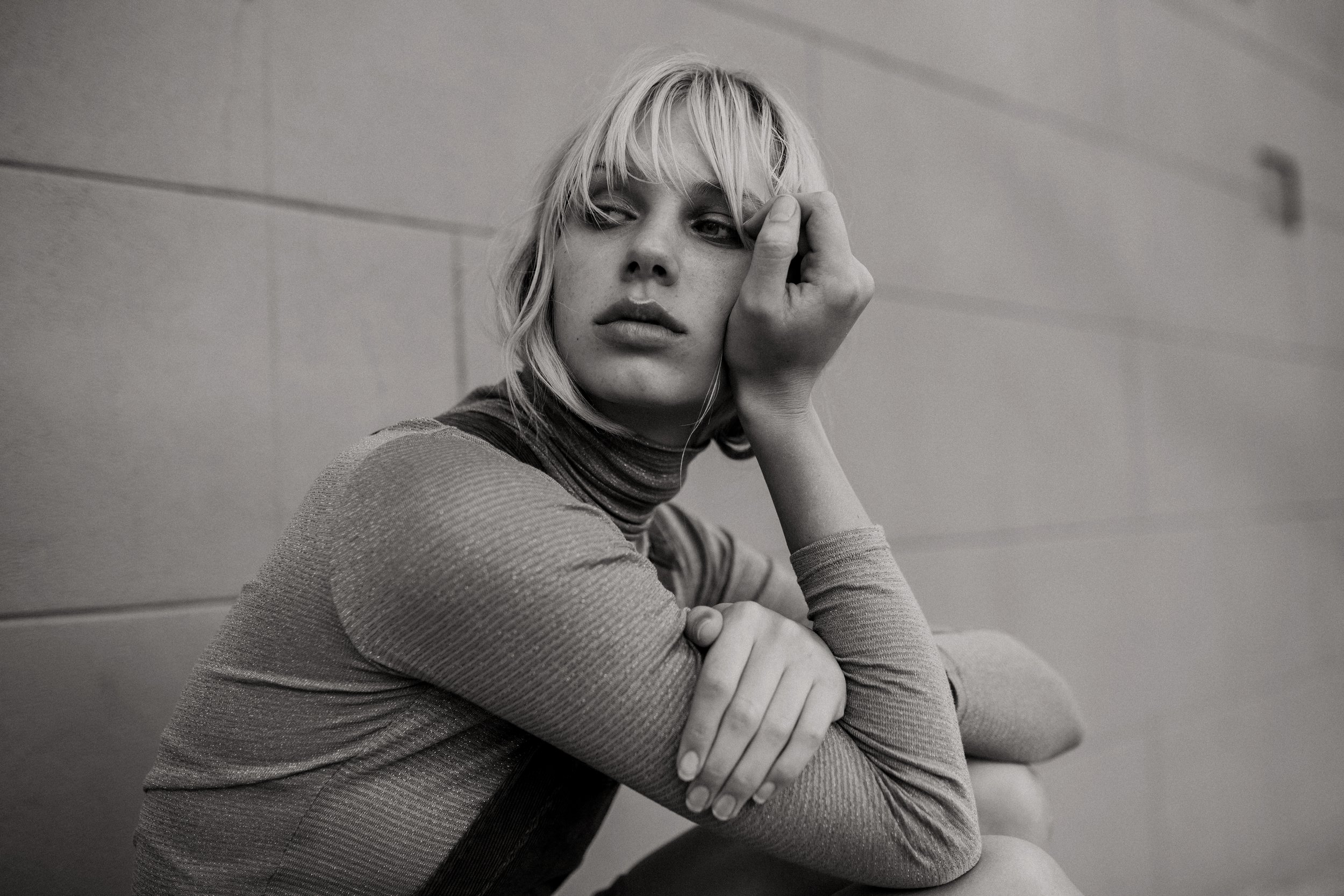 Fashion model crouches with serious expression.