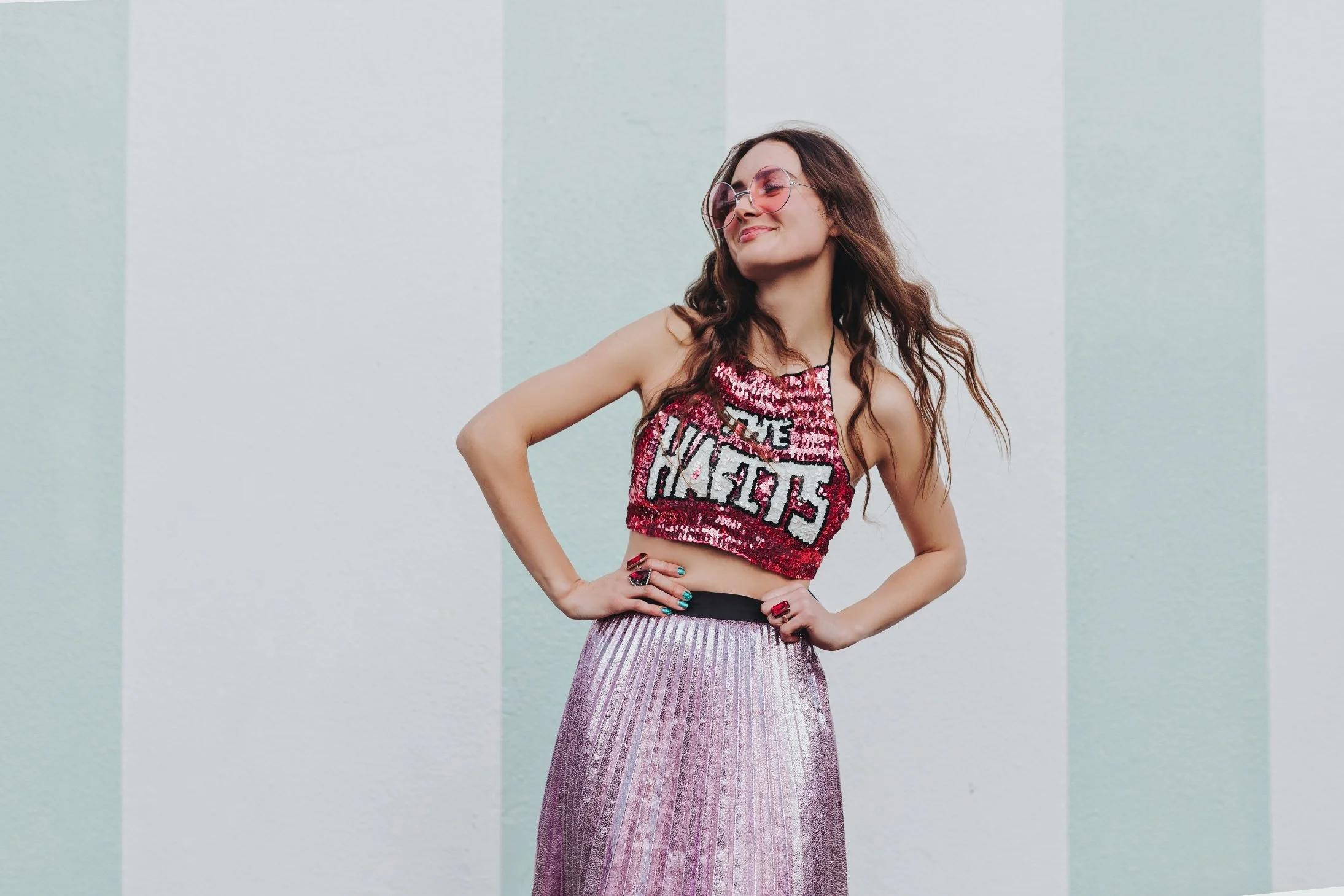 Young musician poses in sequin top and pink skirt for artist profile photography.