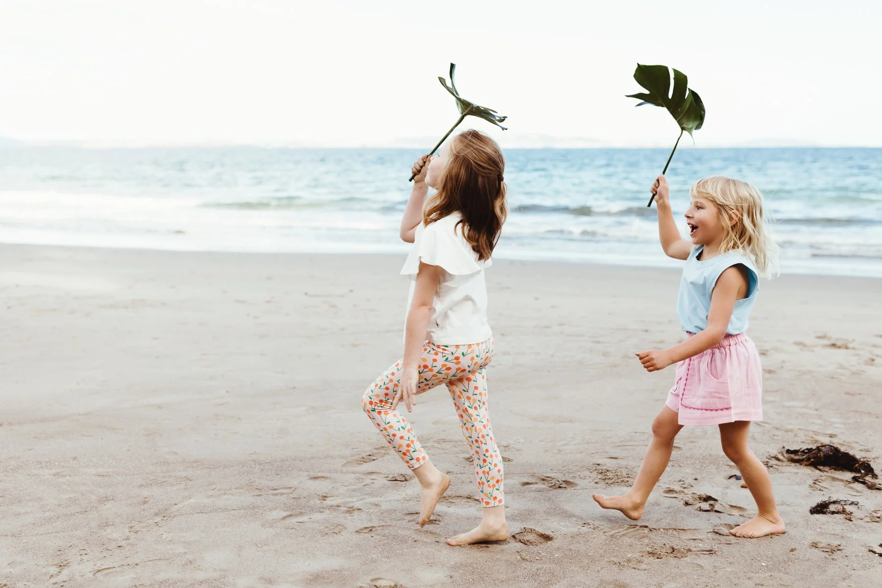 Girls march along beach playfully in fun photo shoot.
