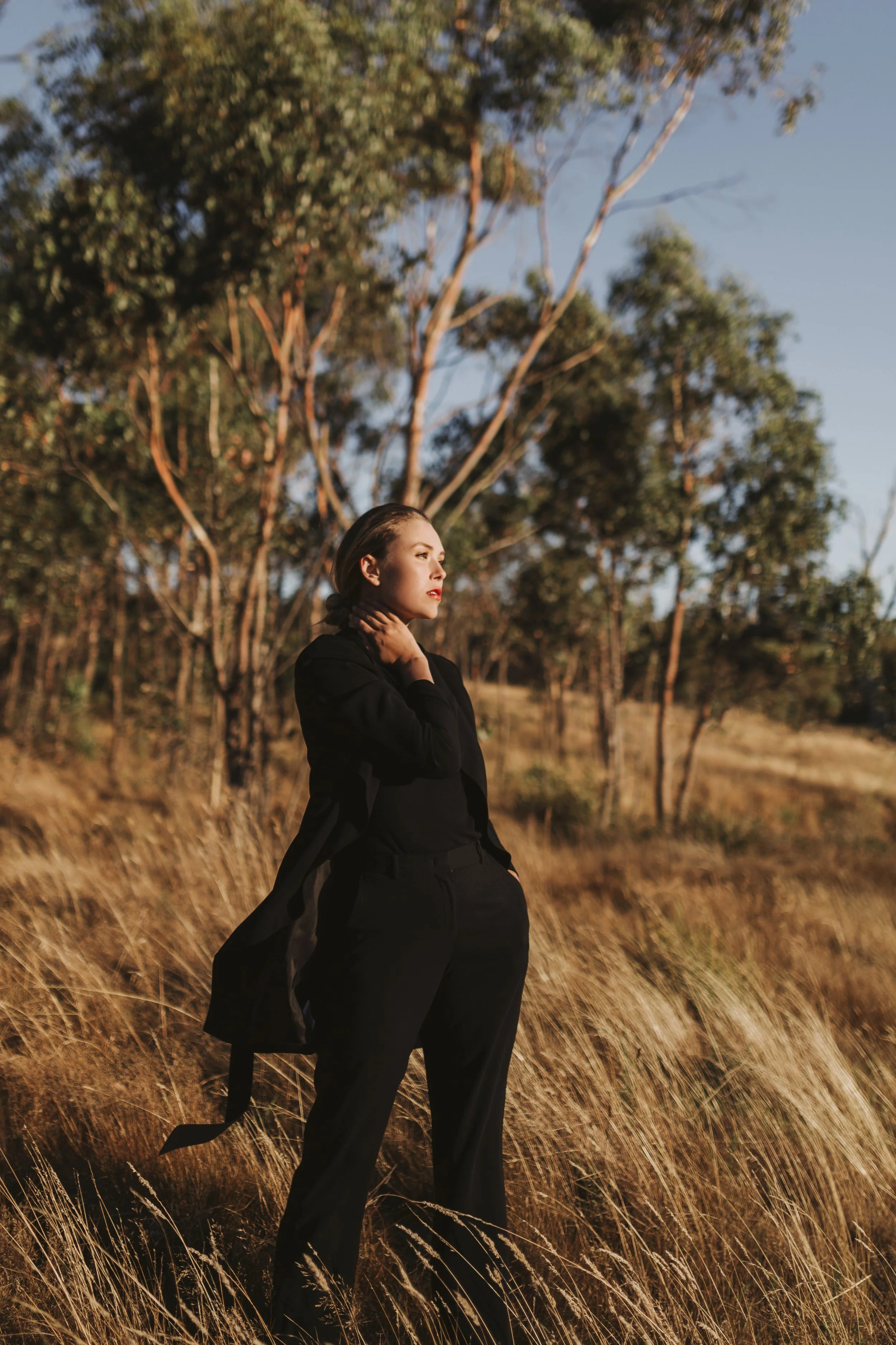 Model stands in field of grass wearing stylish black outfit.