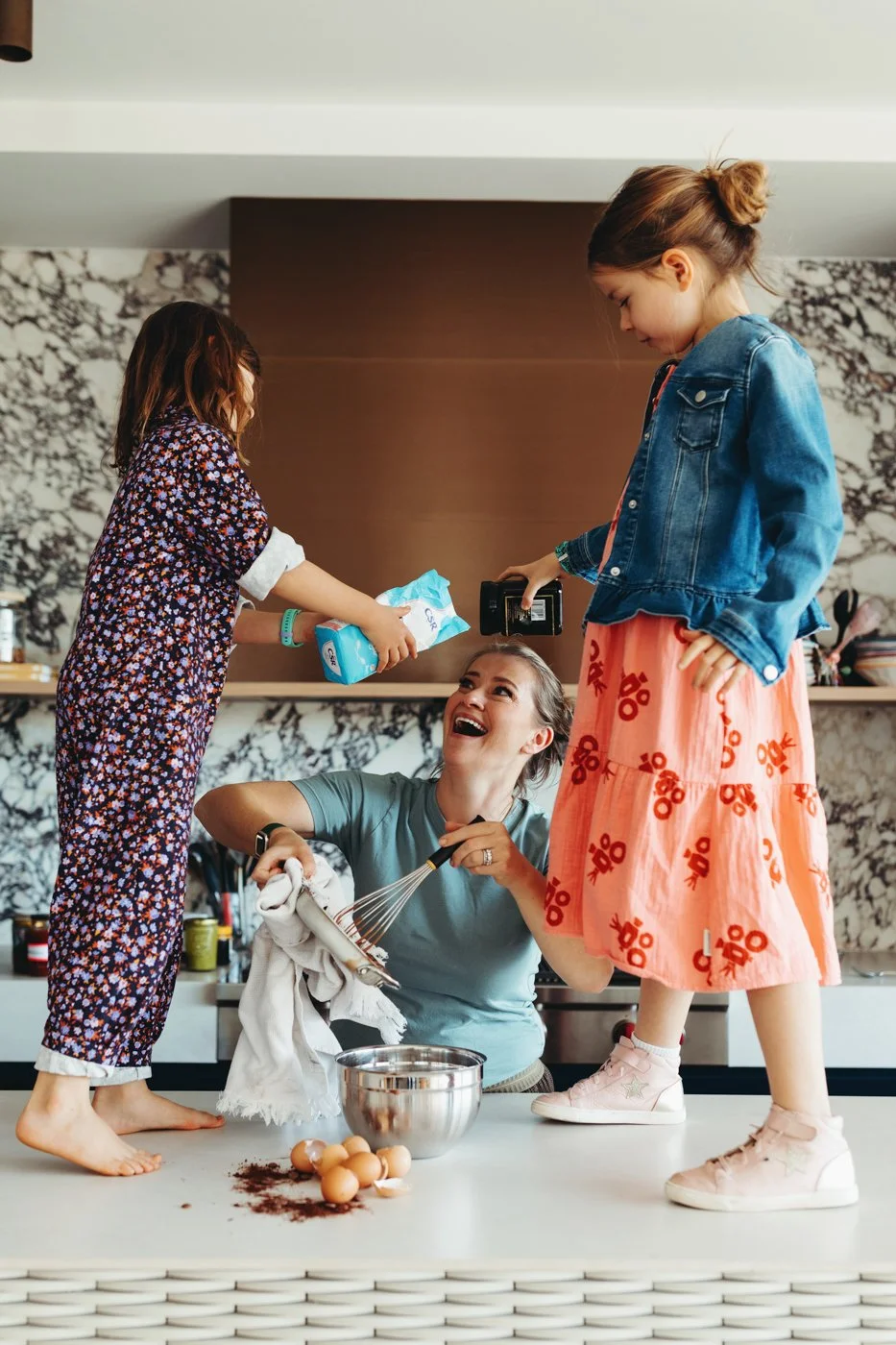 Food author and her daughters bake and laugh together for recipe book photography.