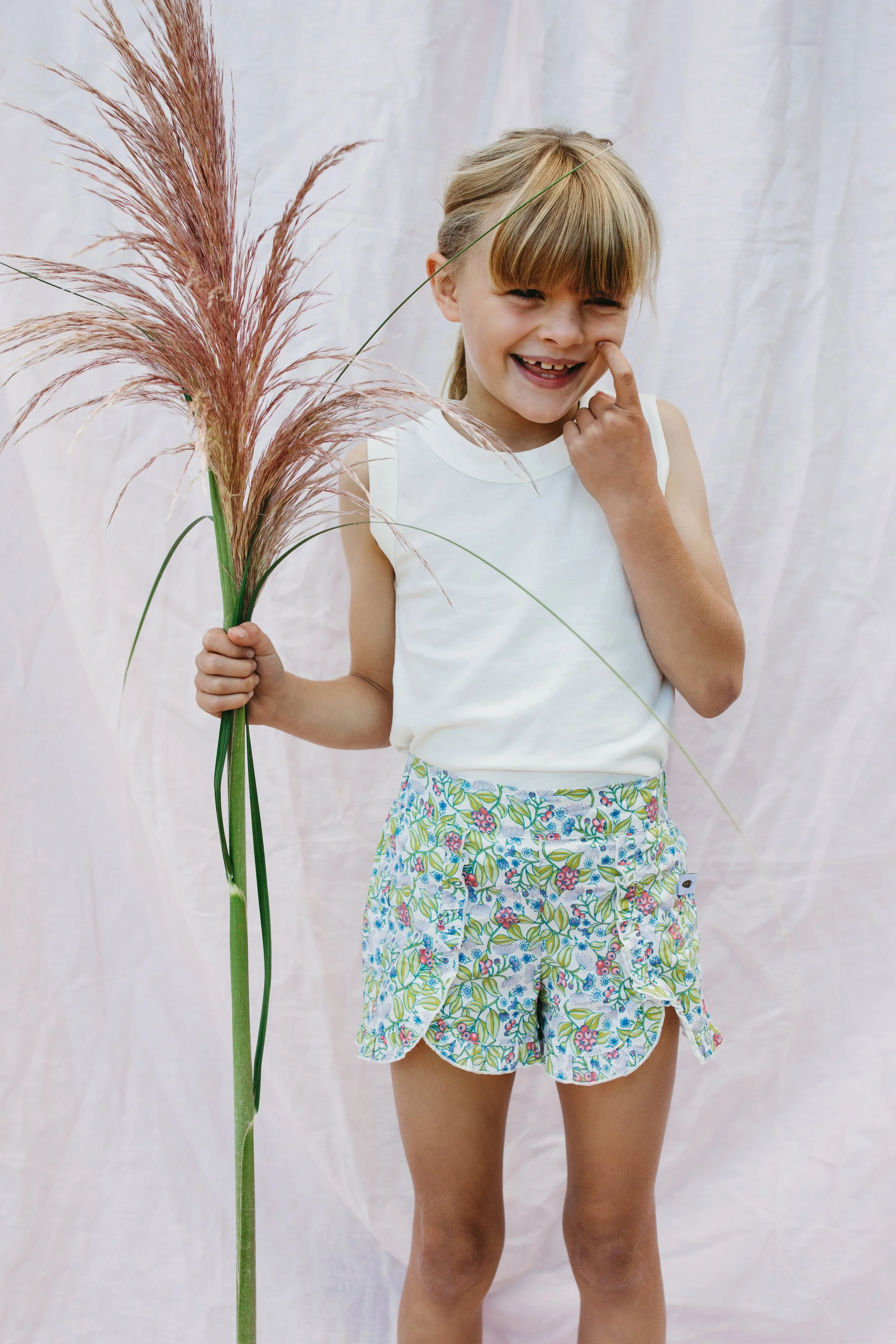 Young girl smiles holding plant during photo shoot.