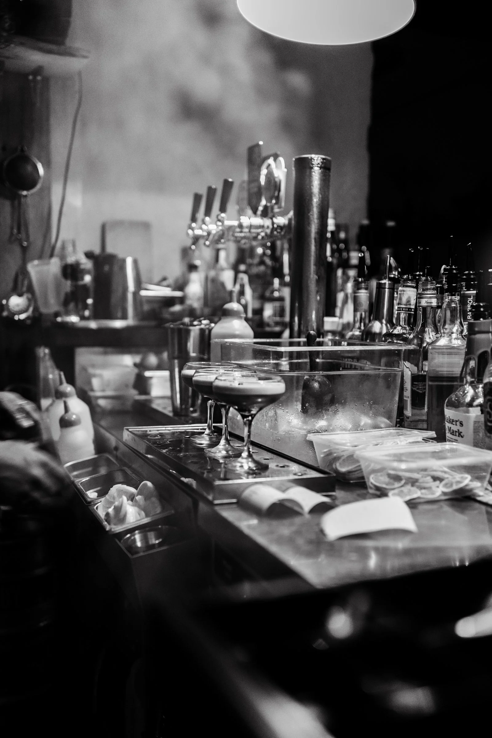 Cocktails sit on bar in black and white photograph.