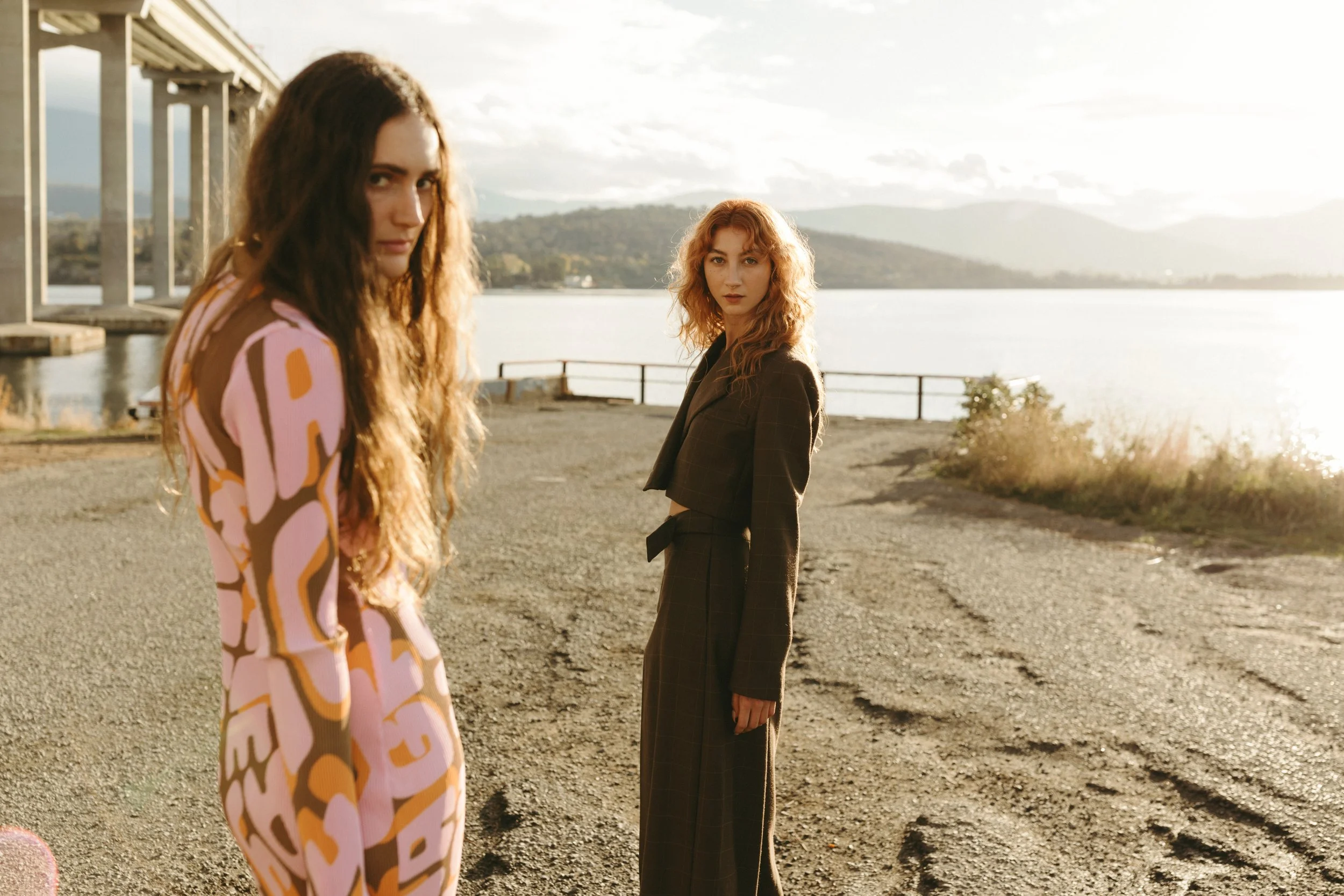 Two models pose beside river during Hobart photo shoot.